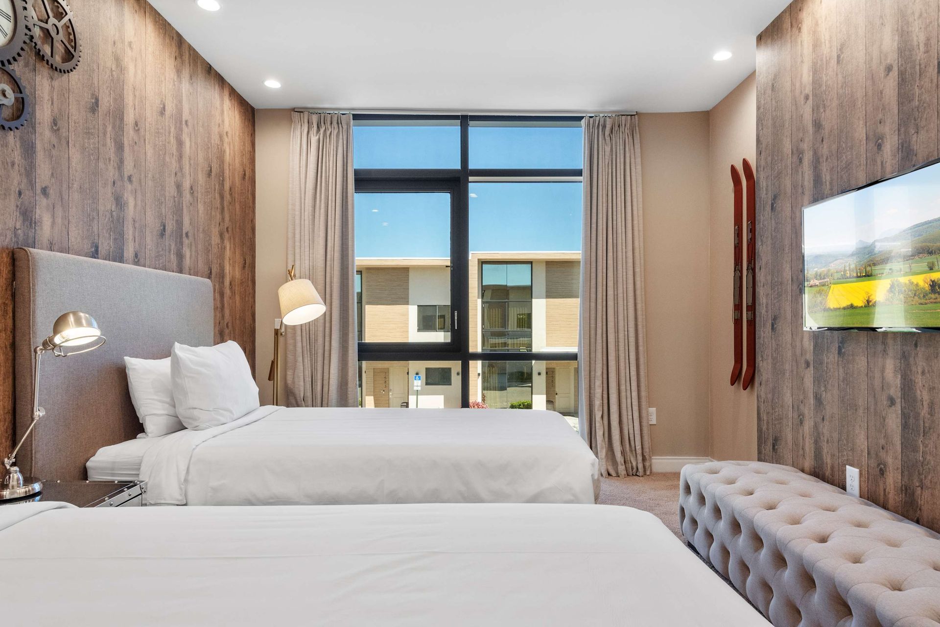 Bright twin room with rustic wood accents, smart TV, and floor-to-ceiling windows
