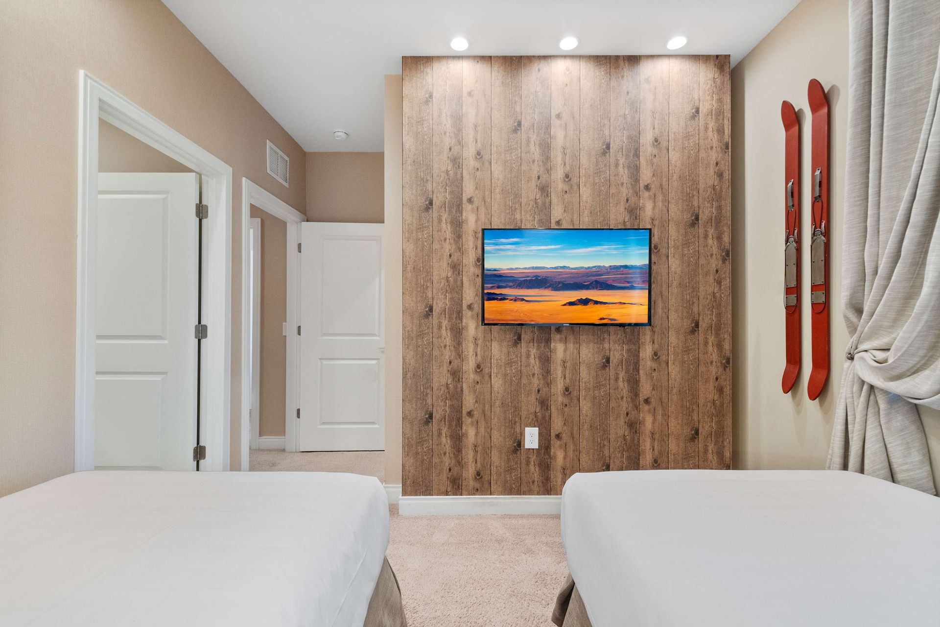 Twin bedroom with wood accent wall, mounted TV, and vintage ski decor for charm
