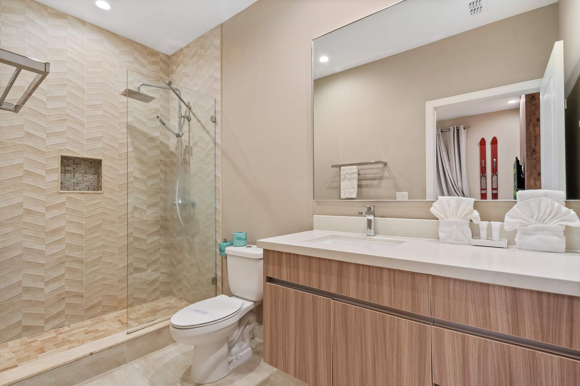 Modern bathroom with sleek vanity, glass walk-in shower, and stylish textured tile
