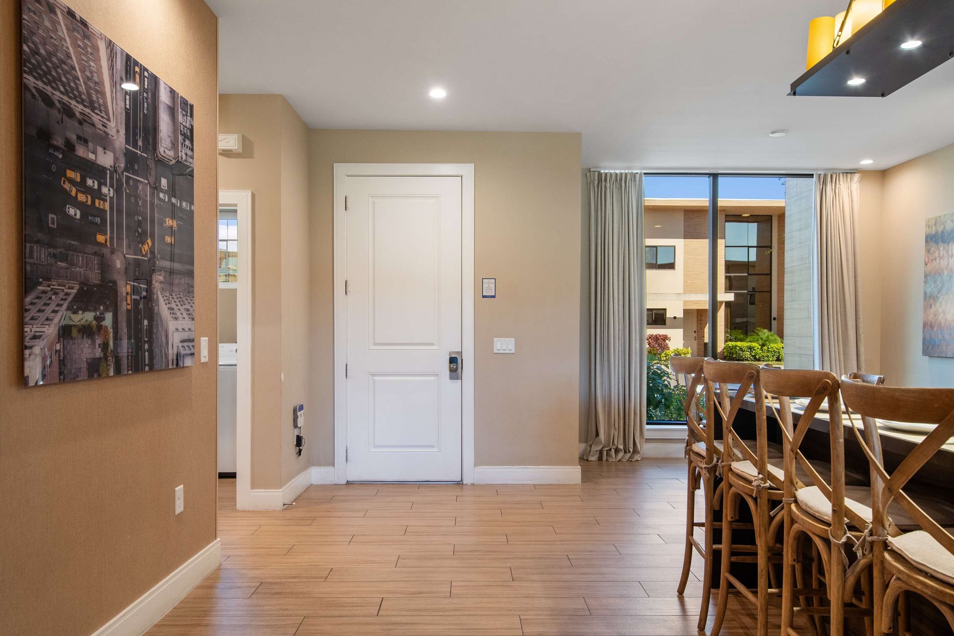 Inviting dining area with rustic chairs, modern art, and bright patio access door.
