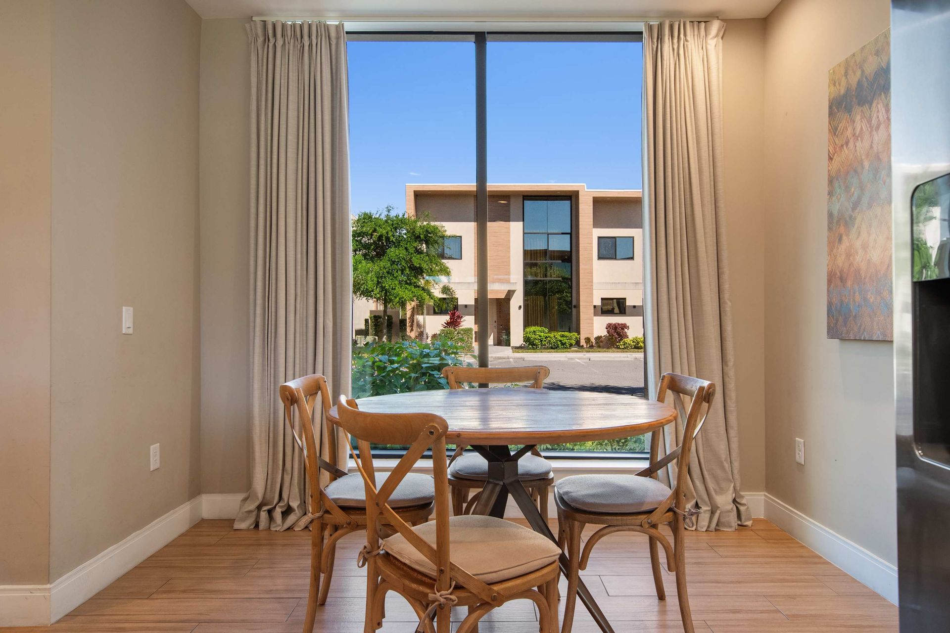 Bright dining nook with large window, natural light, and charming wooden chairs.

