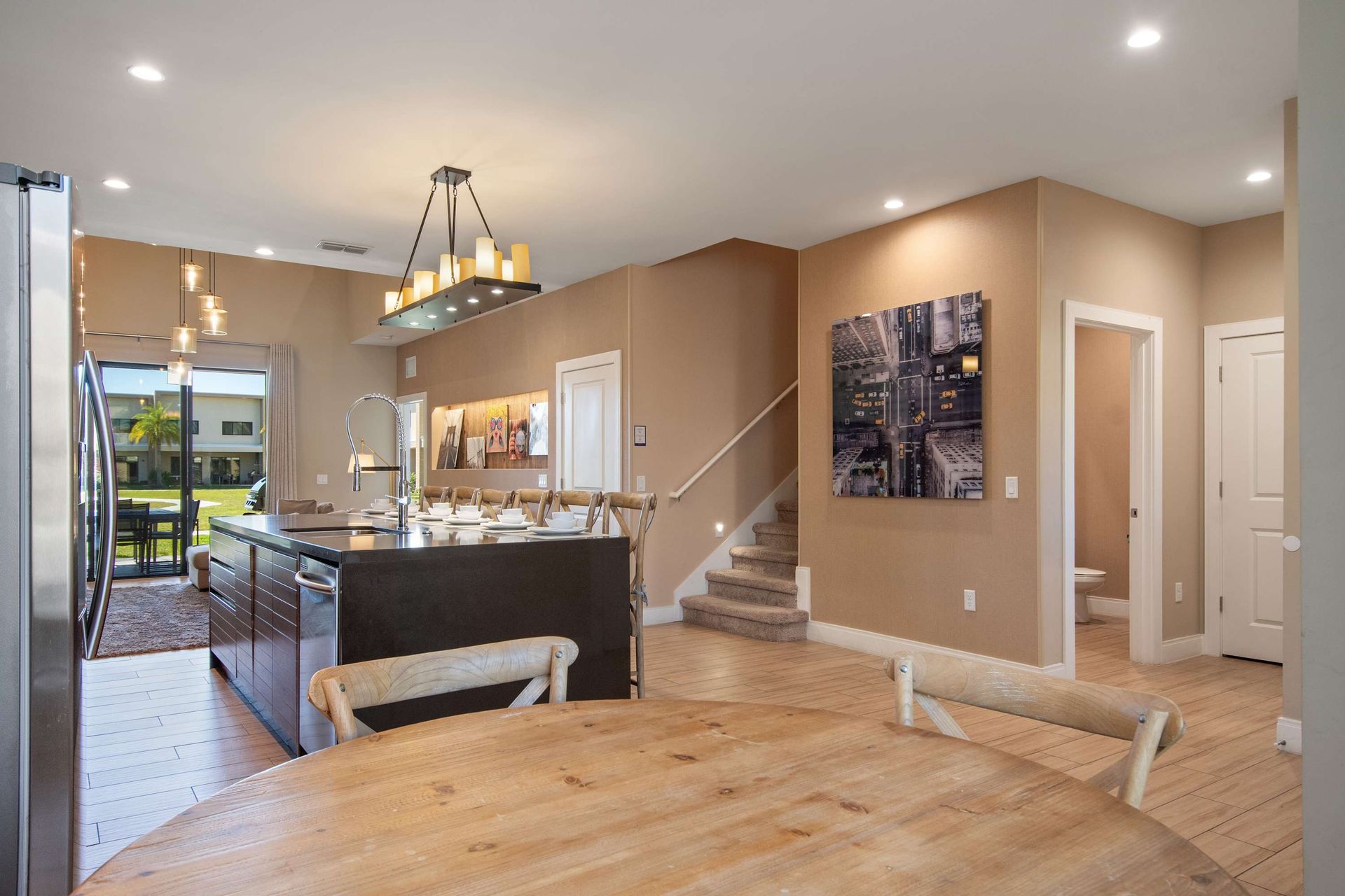 Open concept kitchen and dining with island seating, modern lighting, and patio view.
