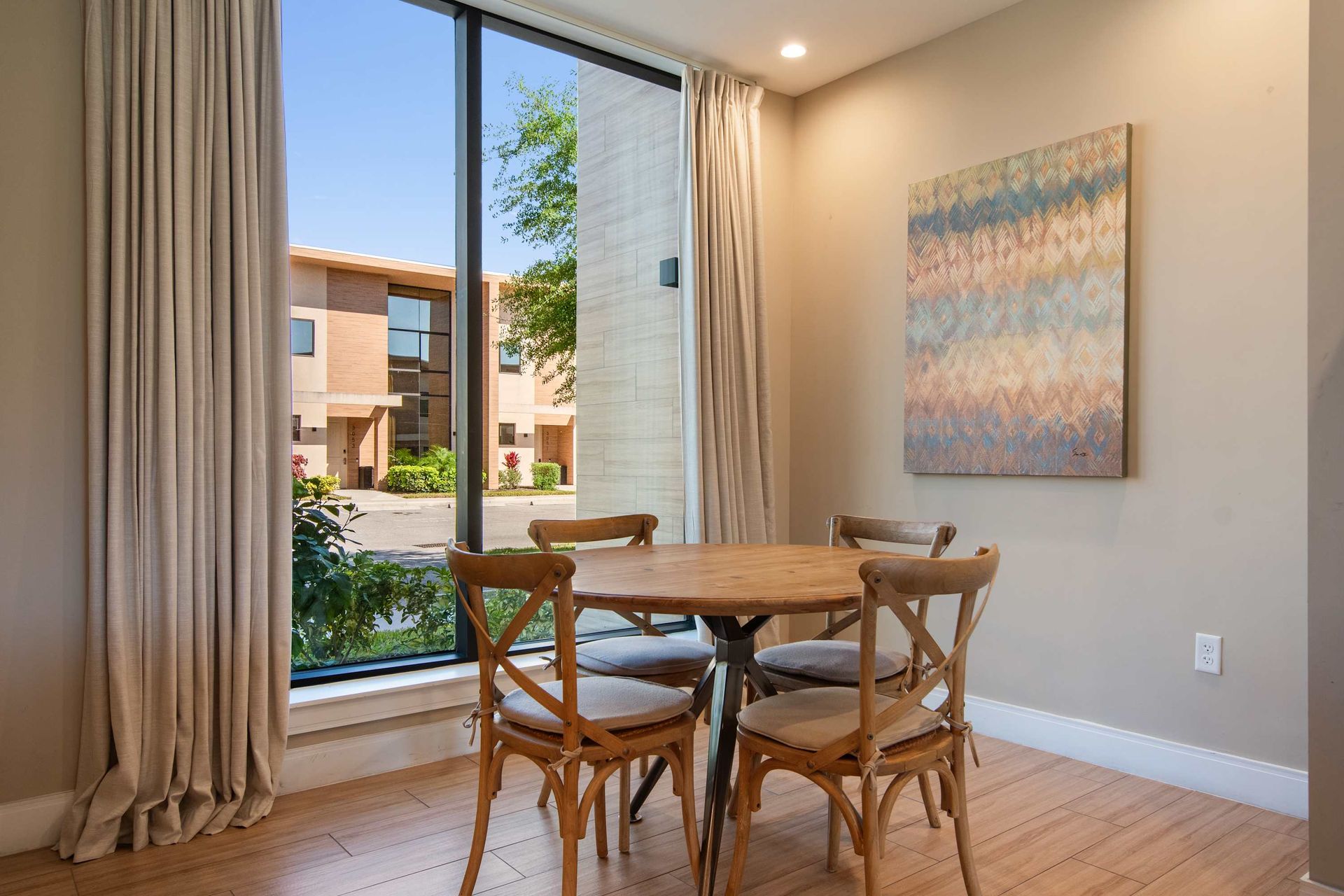 Cozy dining nook with rustic chairs, large window, and peaceful neighborhood view.
