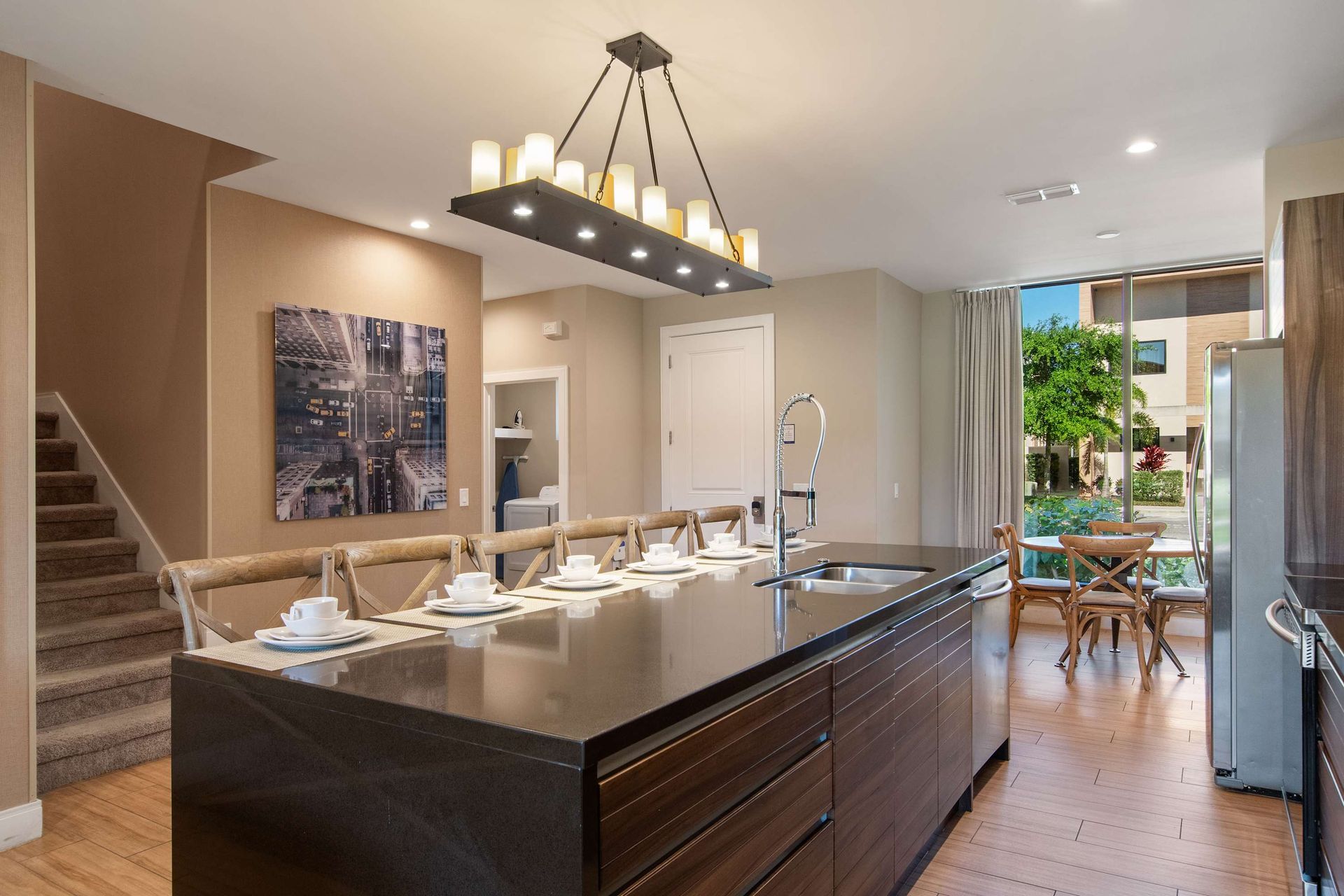 Modern kitchen with sleek island, stylish lighting, breakfast nook, and patio view.
