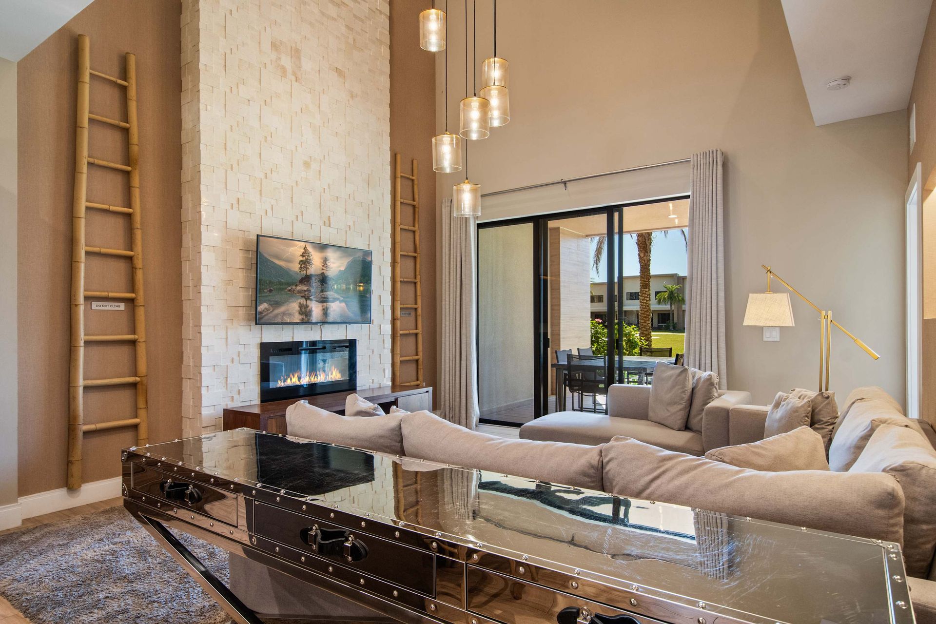 Chic living room with high ceilings, plush sectional, fireplace, and patio access.
