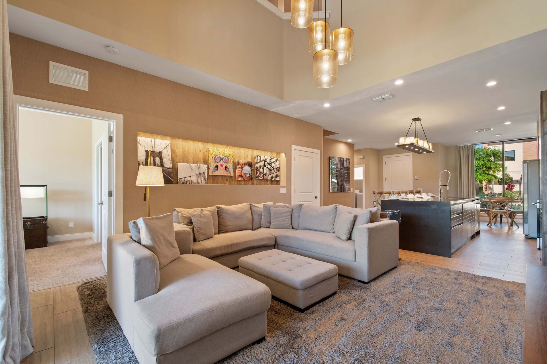 Spacious open living area with plush sectional, chic lighting, and modern kitchen.
