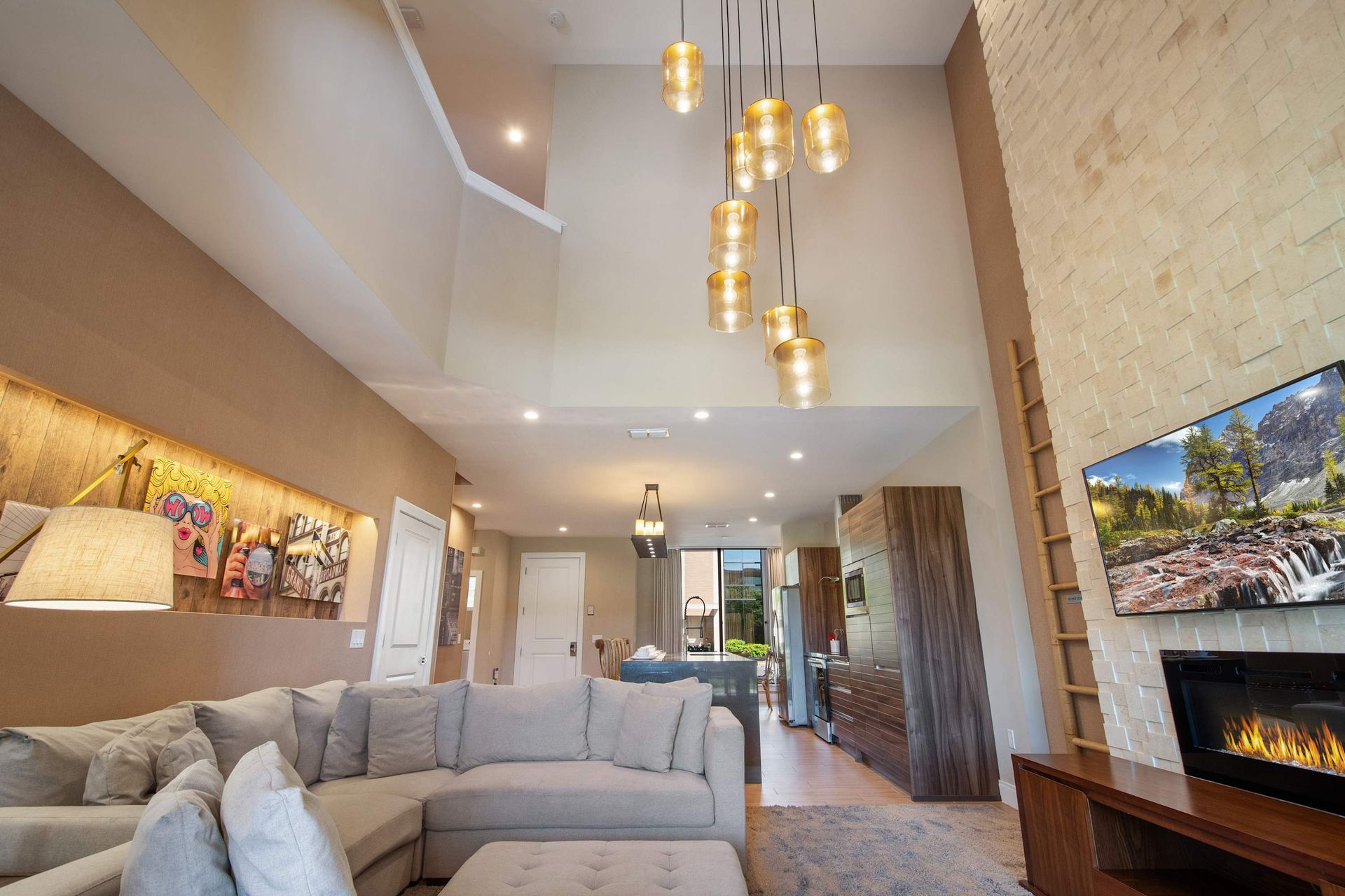 Elegant living room with high ceilings, cozy fireplace, plush sectional, and lights.
