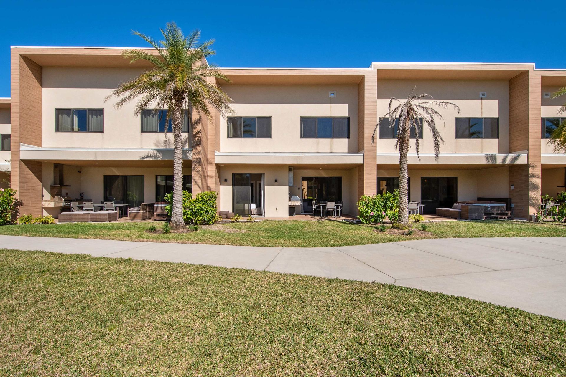 Modern townhome with private patio, lush green courtyard, and relaxing palm trees.
