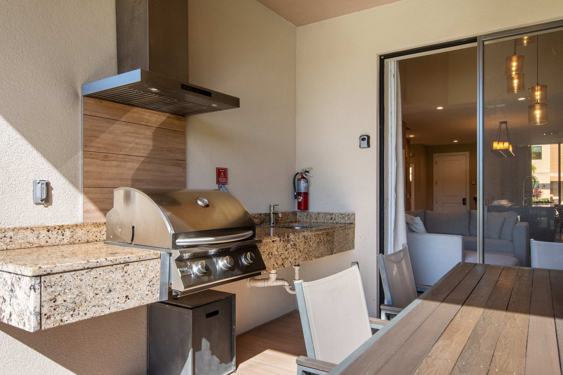 Private patio with built-in grill, granite counter, dining table, and cozy seating.
