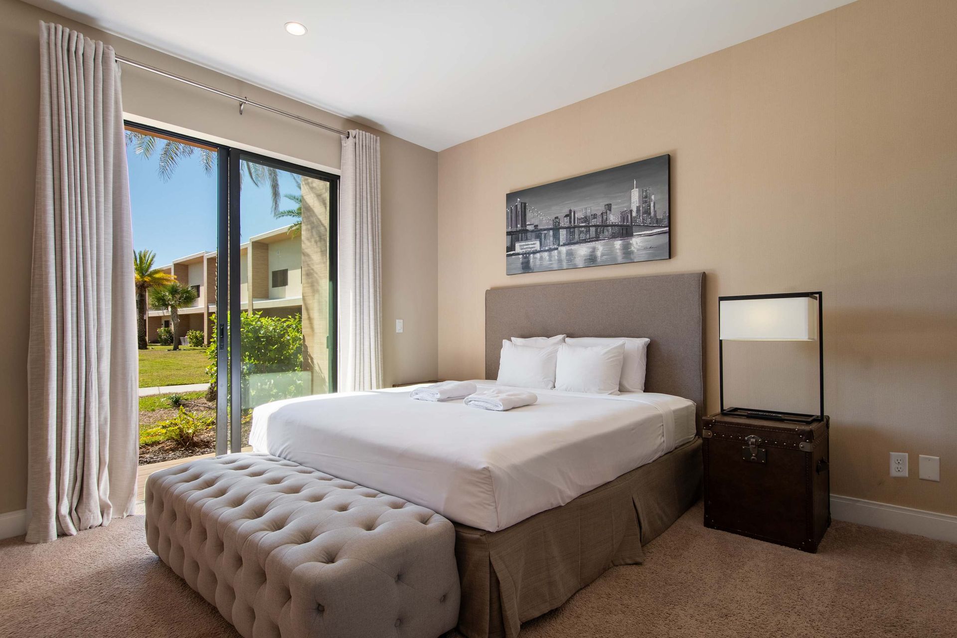 Bright bedroom with plush king bed, patio access, elegant decor, and garden view.
