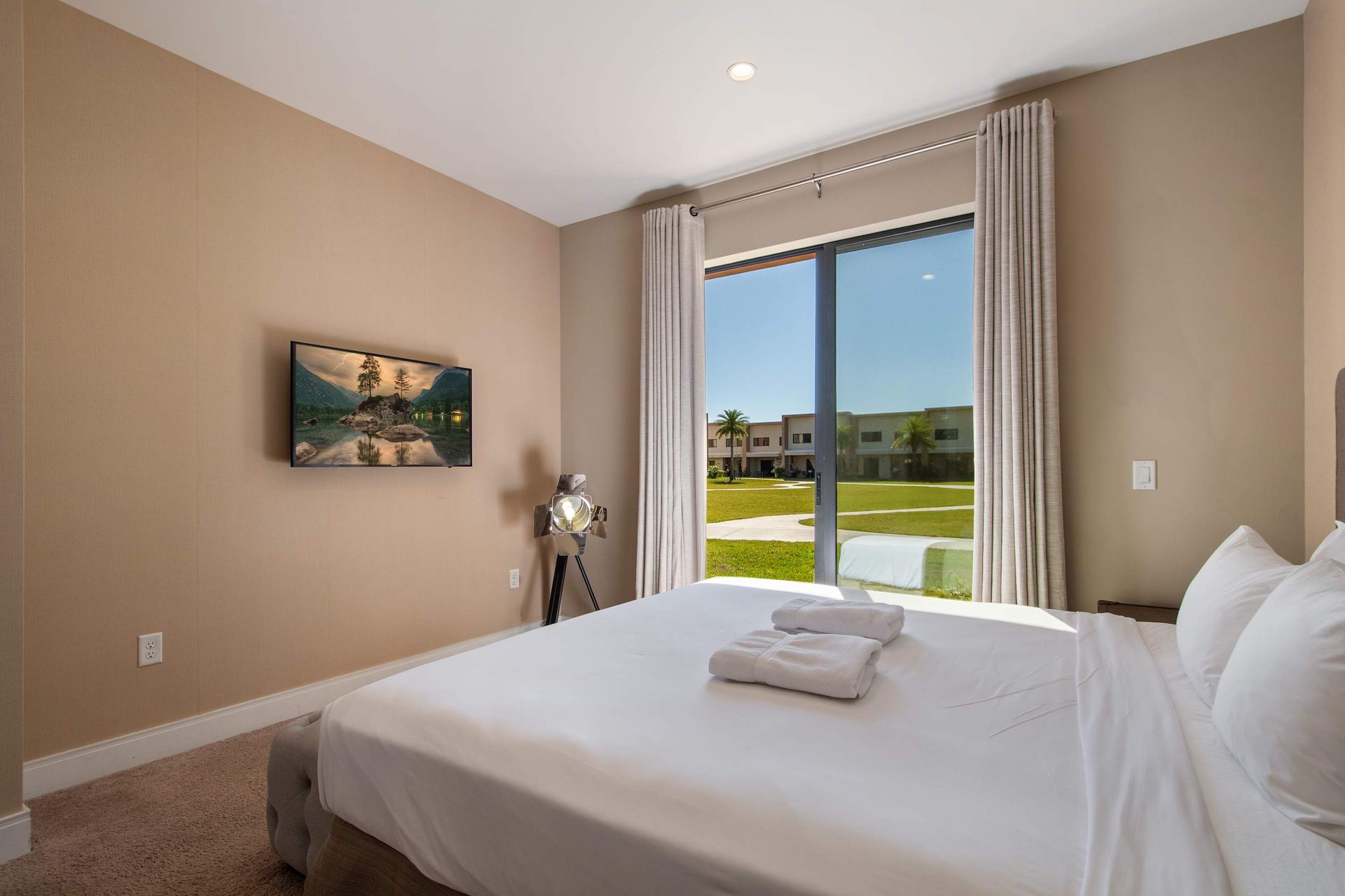 Sunny bedroom with comfy bed, patio door, modern decor, and peaceful courtyard view.
