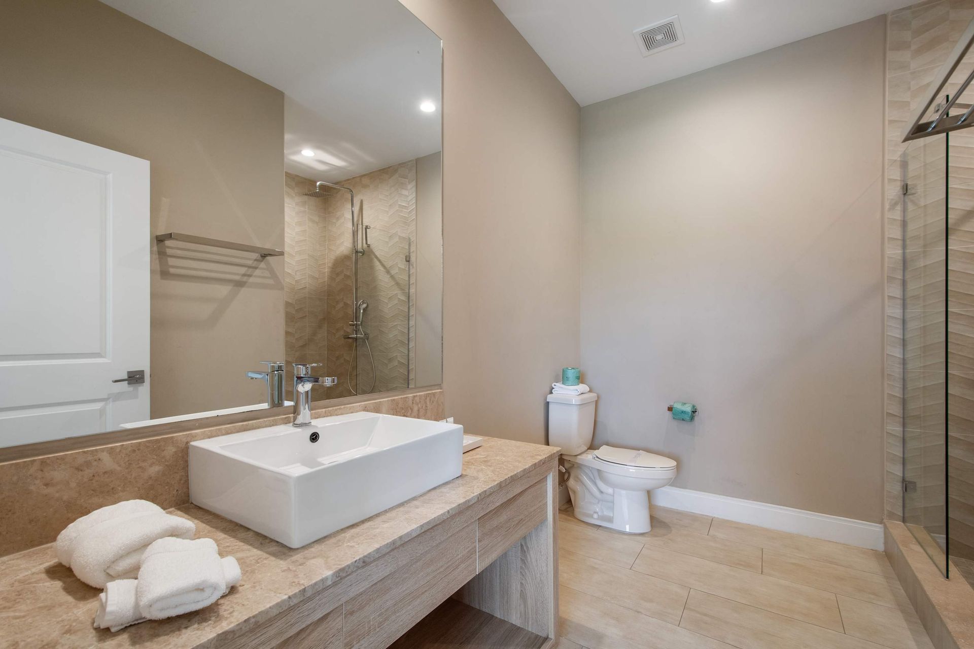 Spacious modern bathroom with large vanity, glass shower, and elegant neutral decor.
