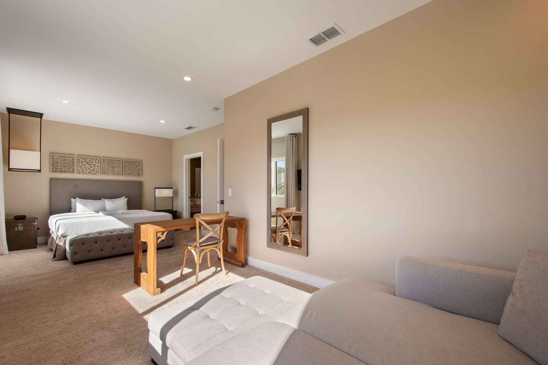 Spacious bedroom with king bed, cozy lounge, work desk, and warm relaxing decor.
