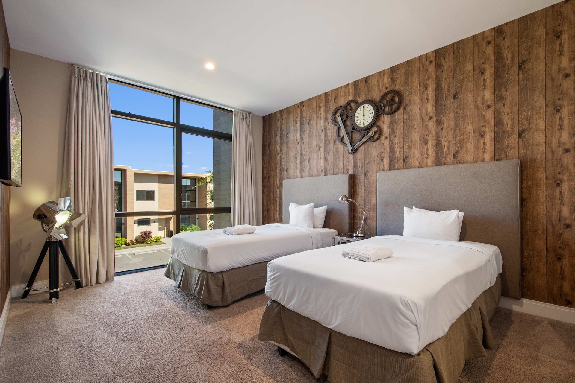 Rustic chic twin bedroom with wood accent wall, large window, and cozy modern feel.
