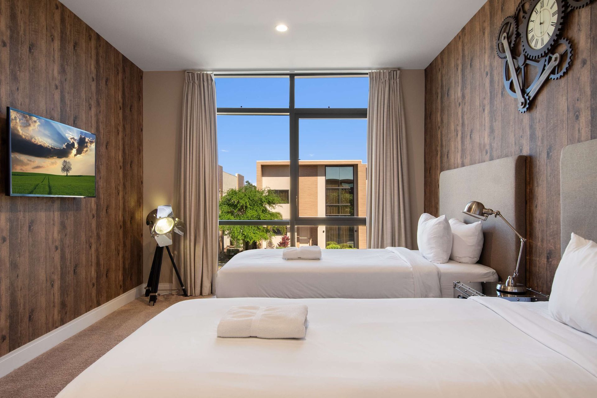 Stylish twin bedroom with rustic accents, large window, and relaxing modern vibe.
