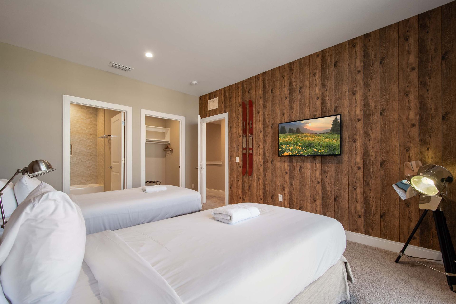 Rustic twin bedroom with wood accent wall, modern TV, cozy beds, and walk-in closet.
