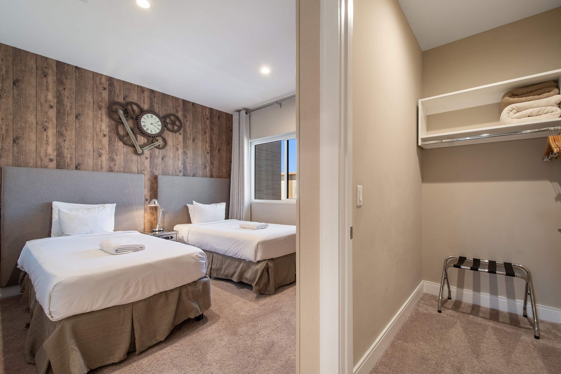 Rustic twin bedroom with wood accent wall, modern TV, cozy beds, and walk-in closet.

