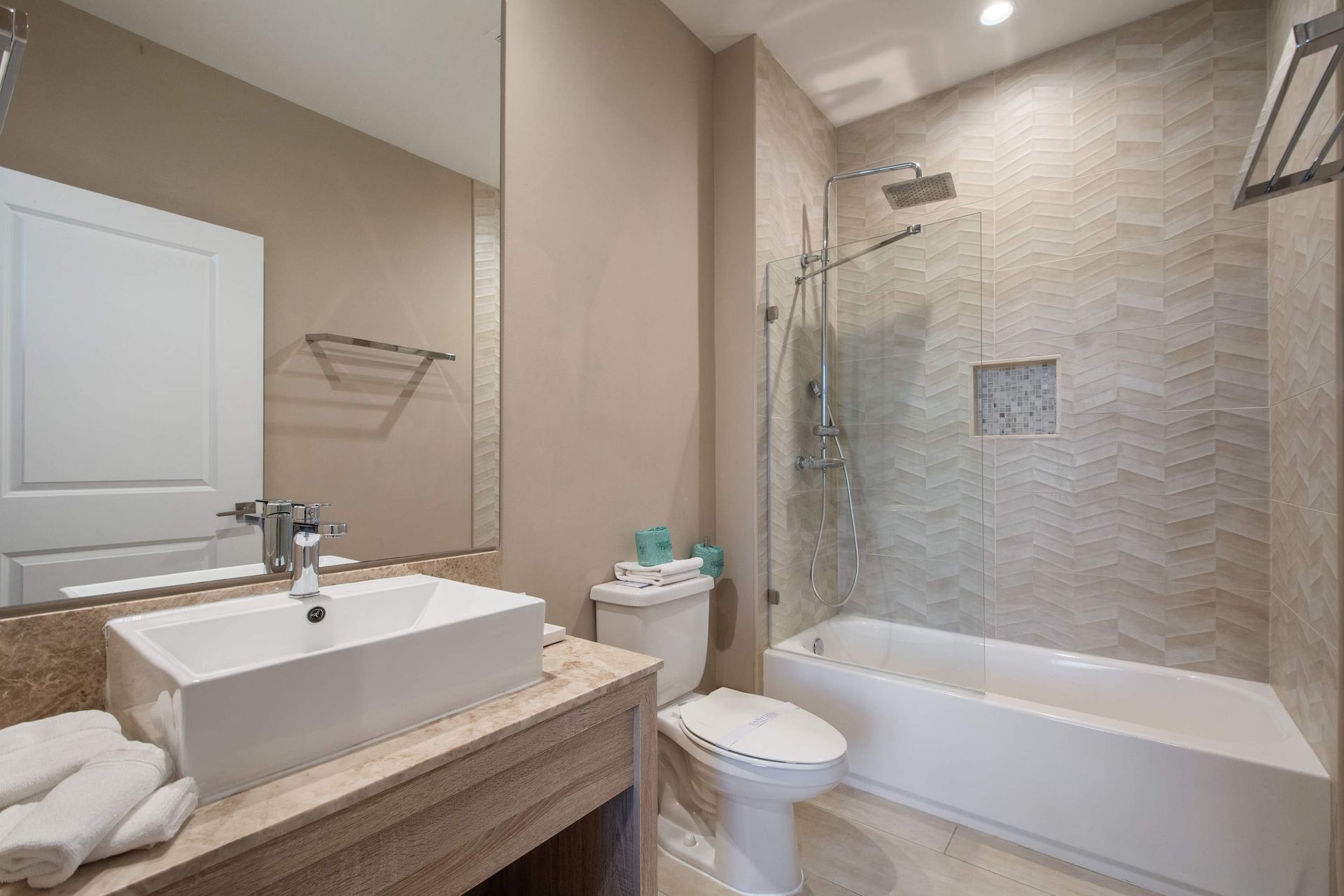 Stylish bathroom with modern vanity, large mirror, and elegant shower-tub combo.
