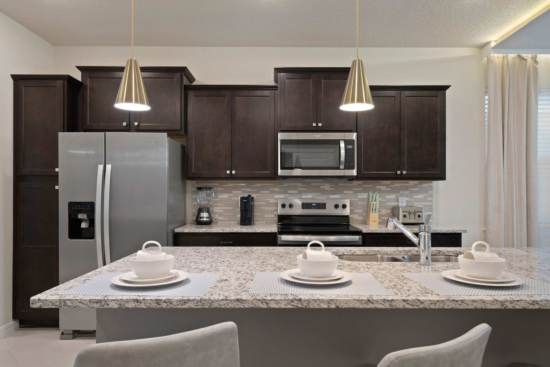 Modern kitchen with granite island, stainless steel appliances, and sleek lighting.
