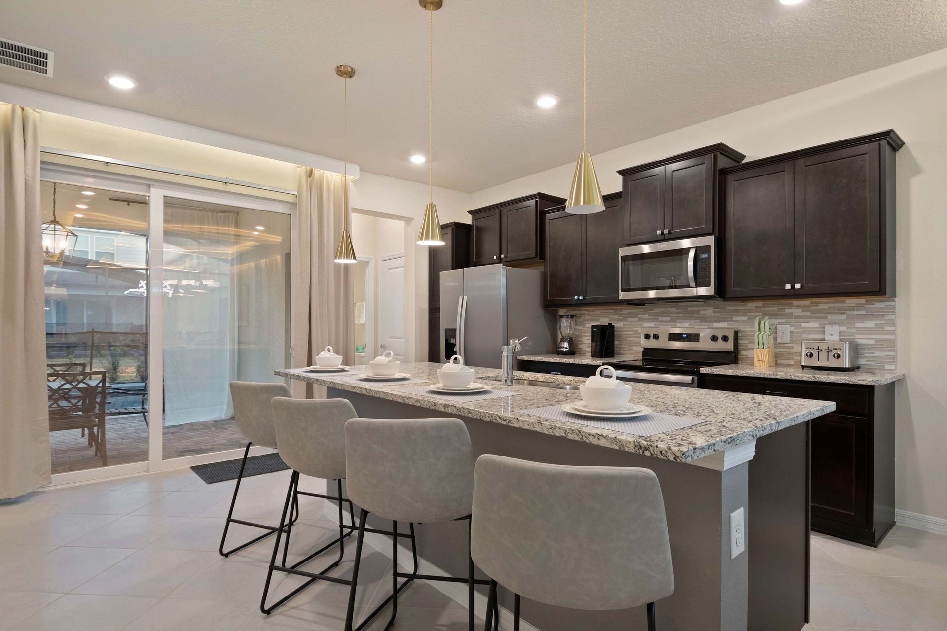 Stylish kitchen with granite island seating, modern appliances, and patio access.
