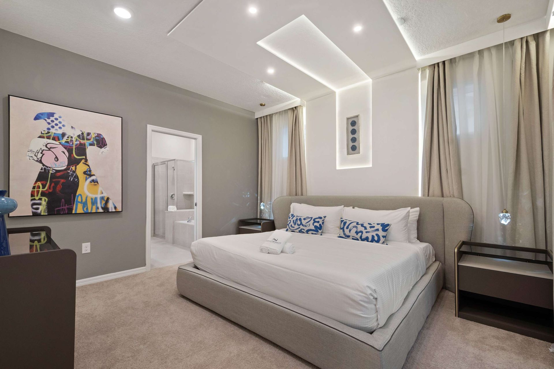 Stylish king bedroom with ensuite bath, artistic flair, and custom ceiling lights.
