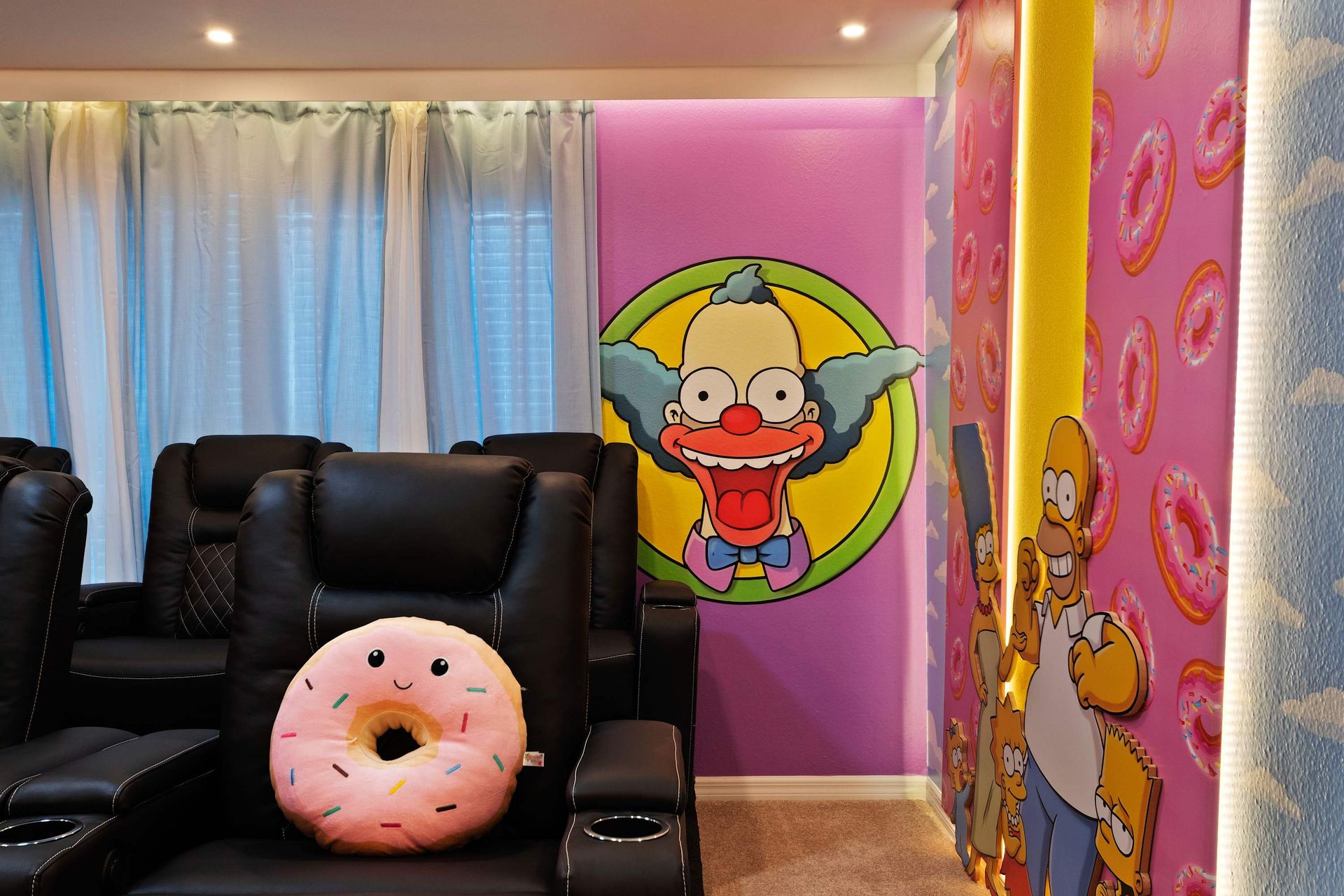 Colorful Simpsons-themed theater with plush seating, fun murals, and donut decor.
