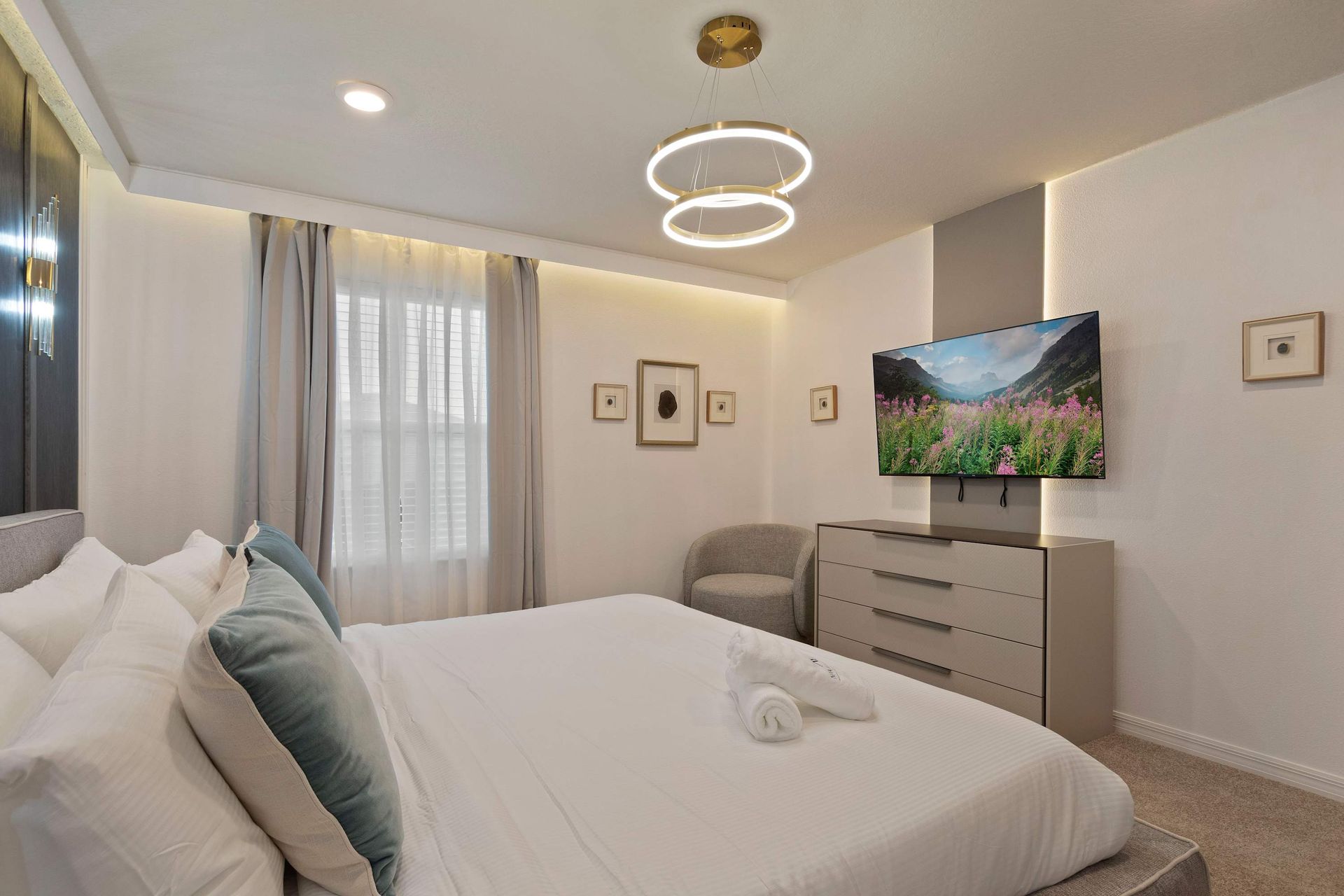 Contemporary king bedroom with soft tones, smart TV, and elegant modern touches.
