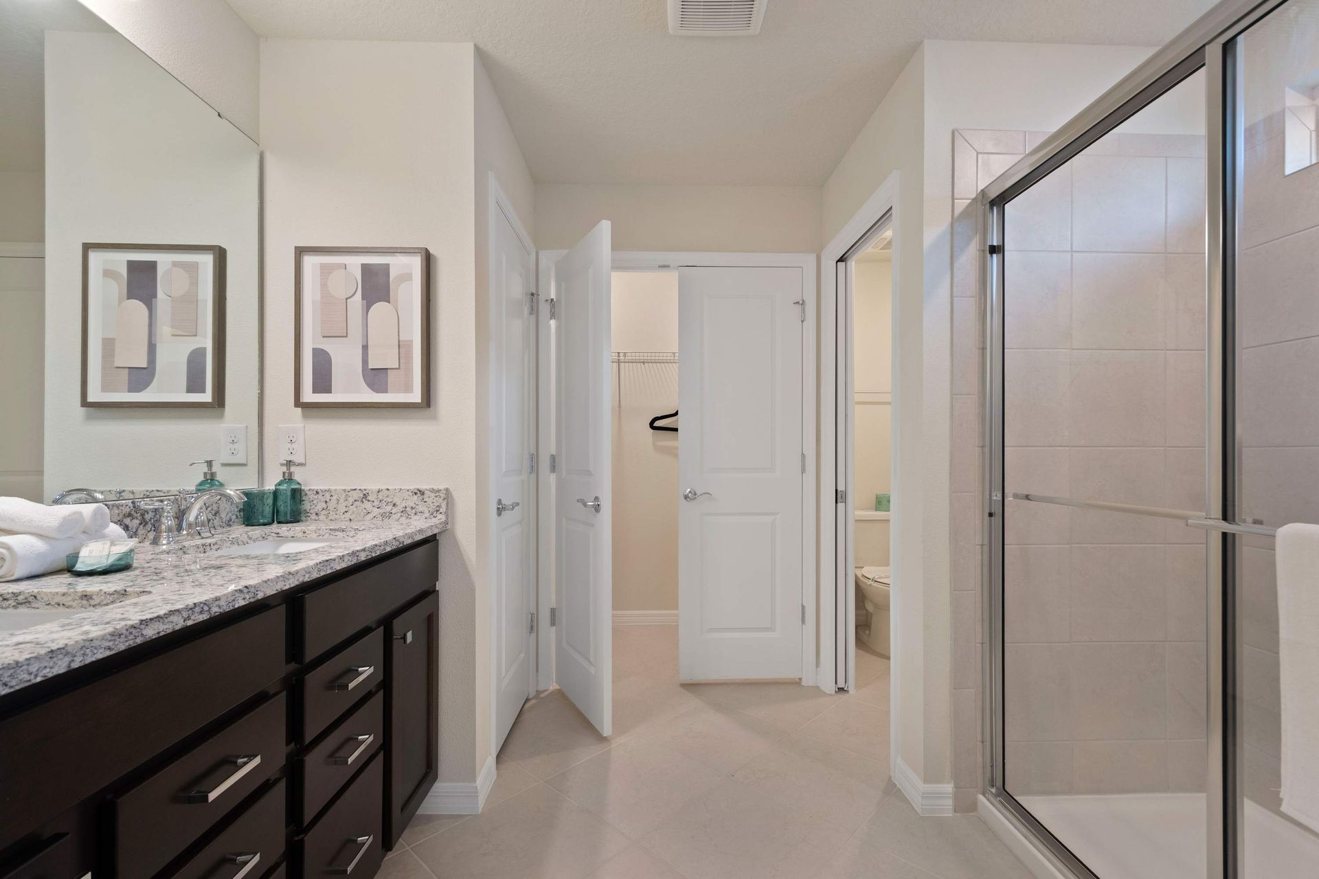 Spacious bathroom with granite double vanity, glass shower, and neutral décor.
