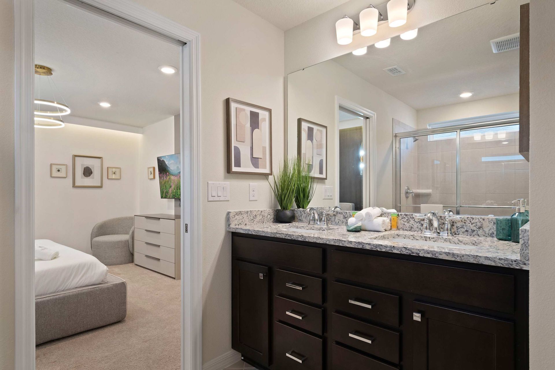 Elegant ensuite bathroom with double vanity, granite counters, and glass shower.

