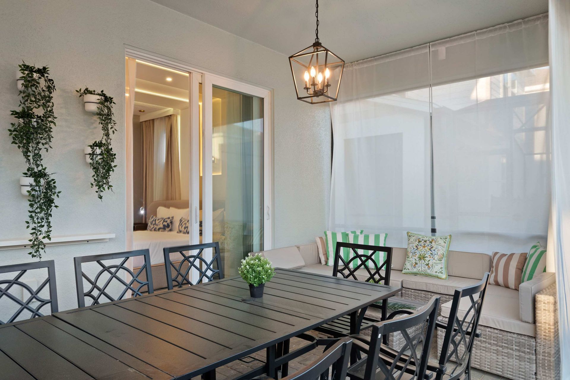 Cozy screened patio with lounge seating, greenery accents, and dining for eight.
