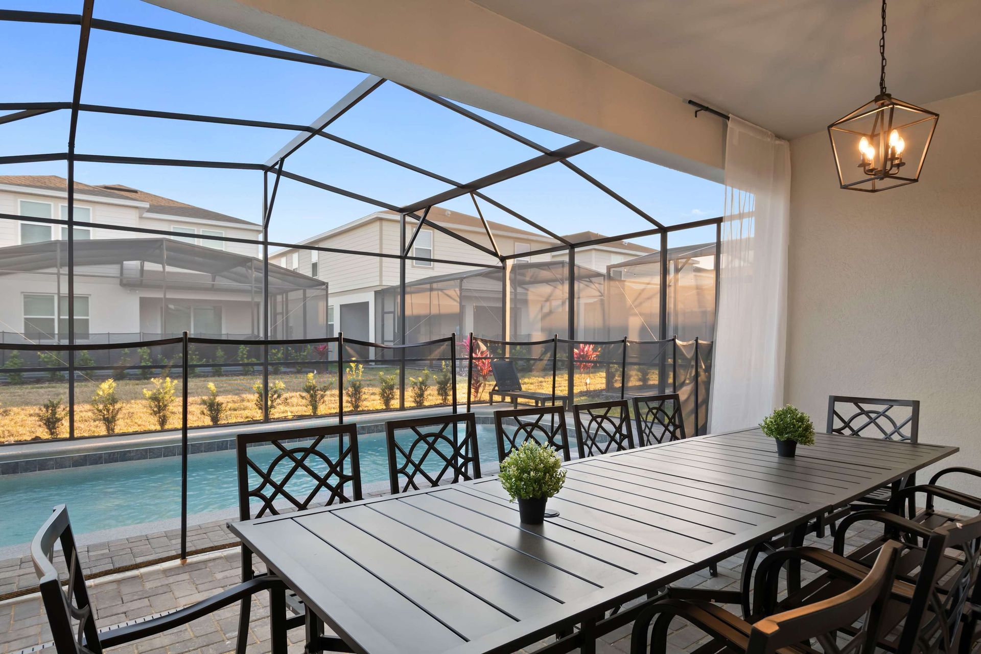 Screened-in patio with pool views, outdoor dining for eight, and stylish lighting.
