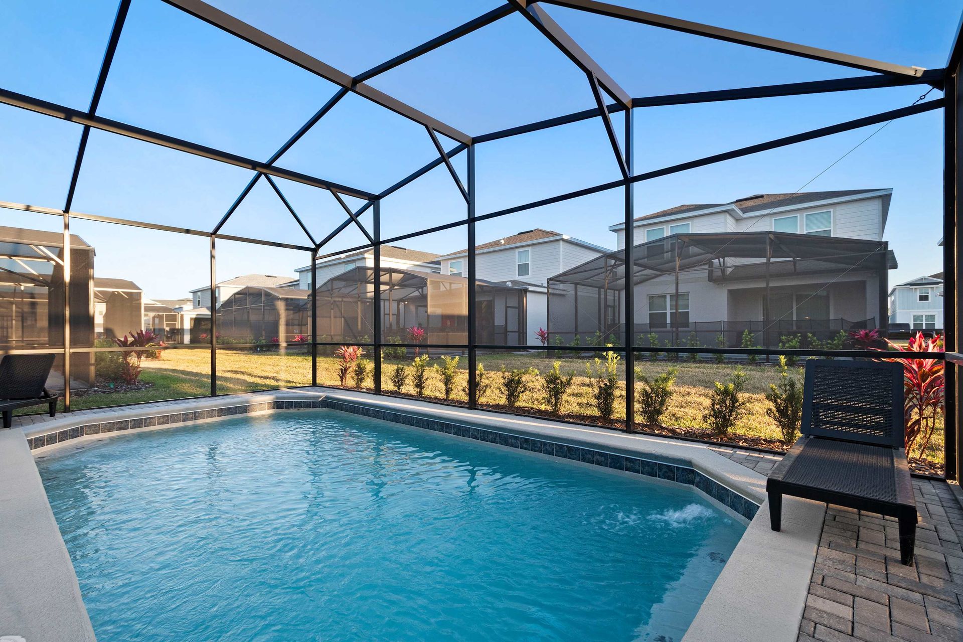 Private screened-in pool with sunny deck, lounge chairs, and peaceful backyard views.
