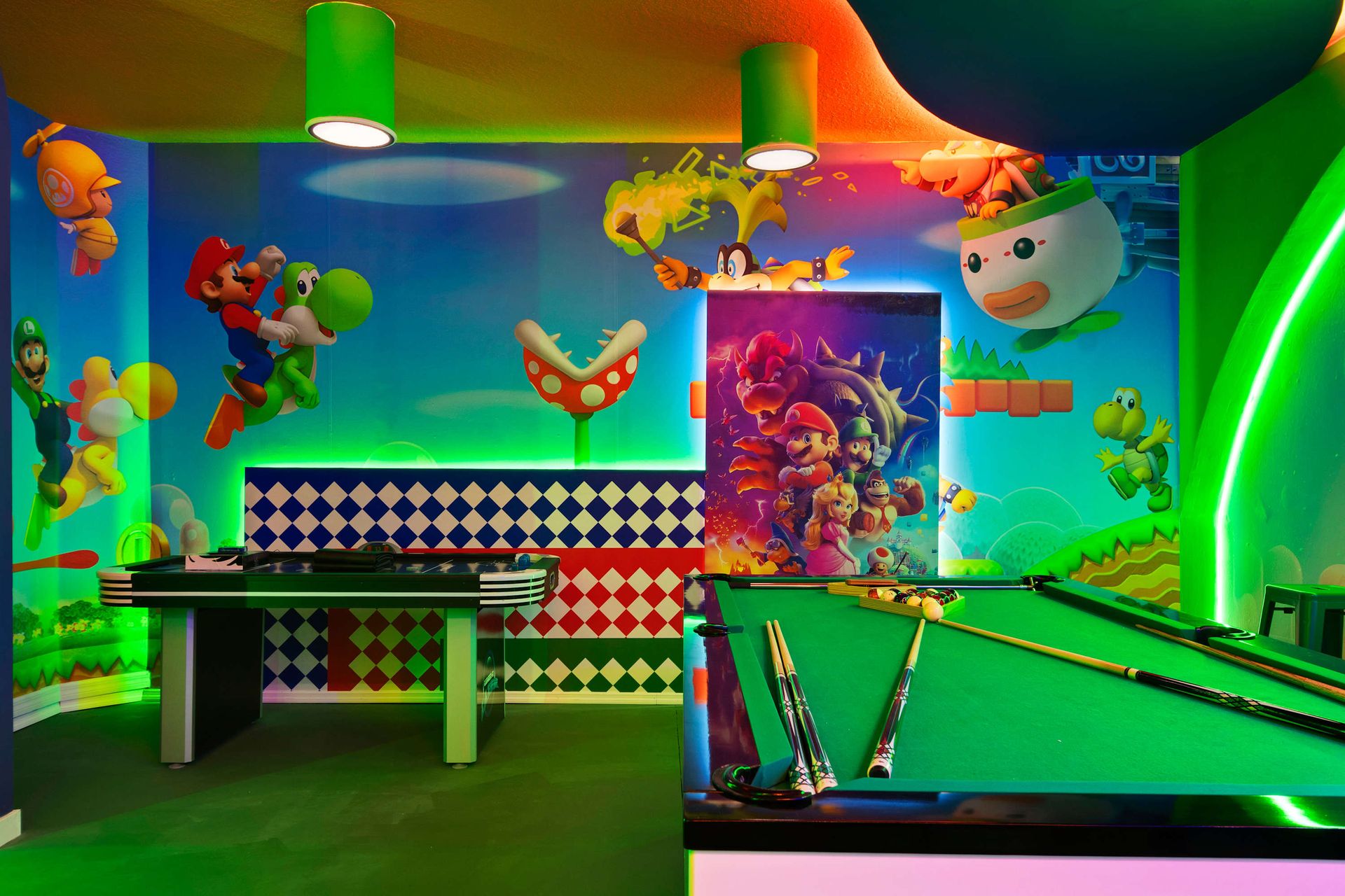 Super Mario-themed game room with pool, air hockey, and glowing wall art.
