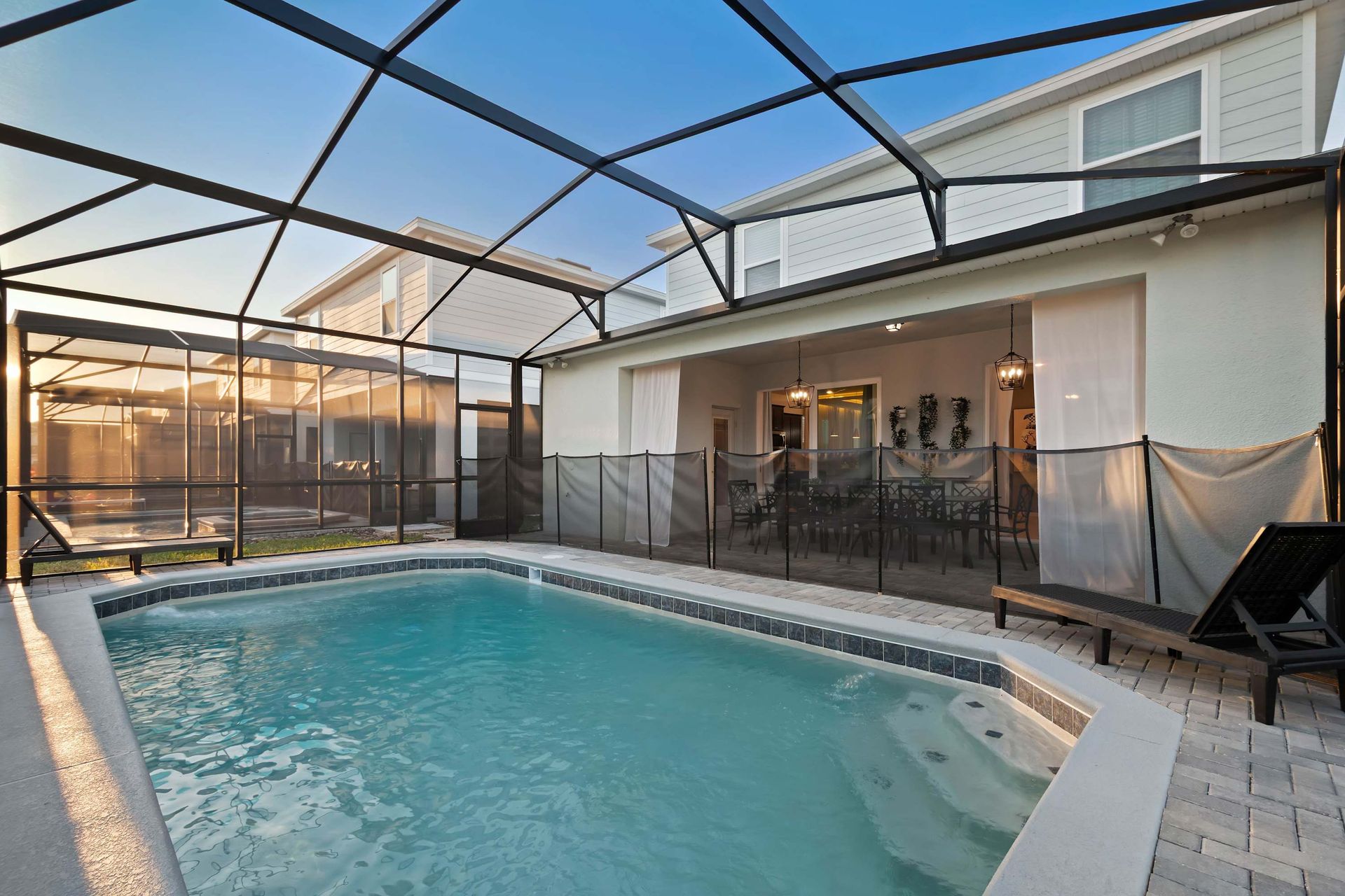 Screened private pool with spa, safety fence, loungers, and covered patio access.
