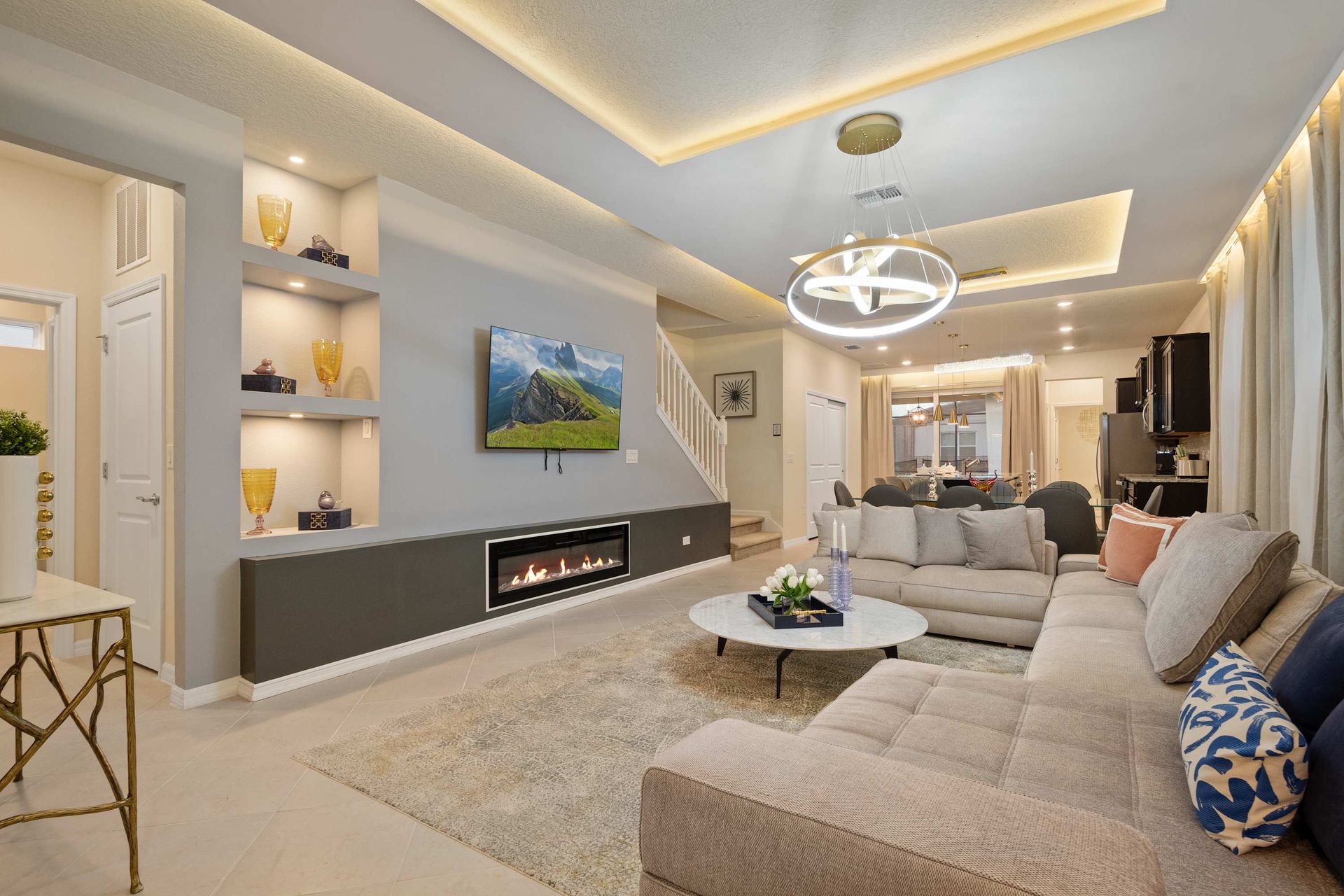 Modern living room with elegant lighting, cozy seating, and built-in fireplace.
