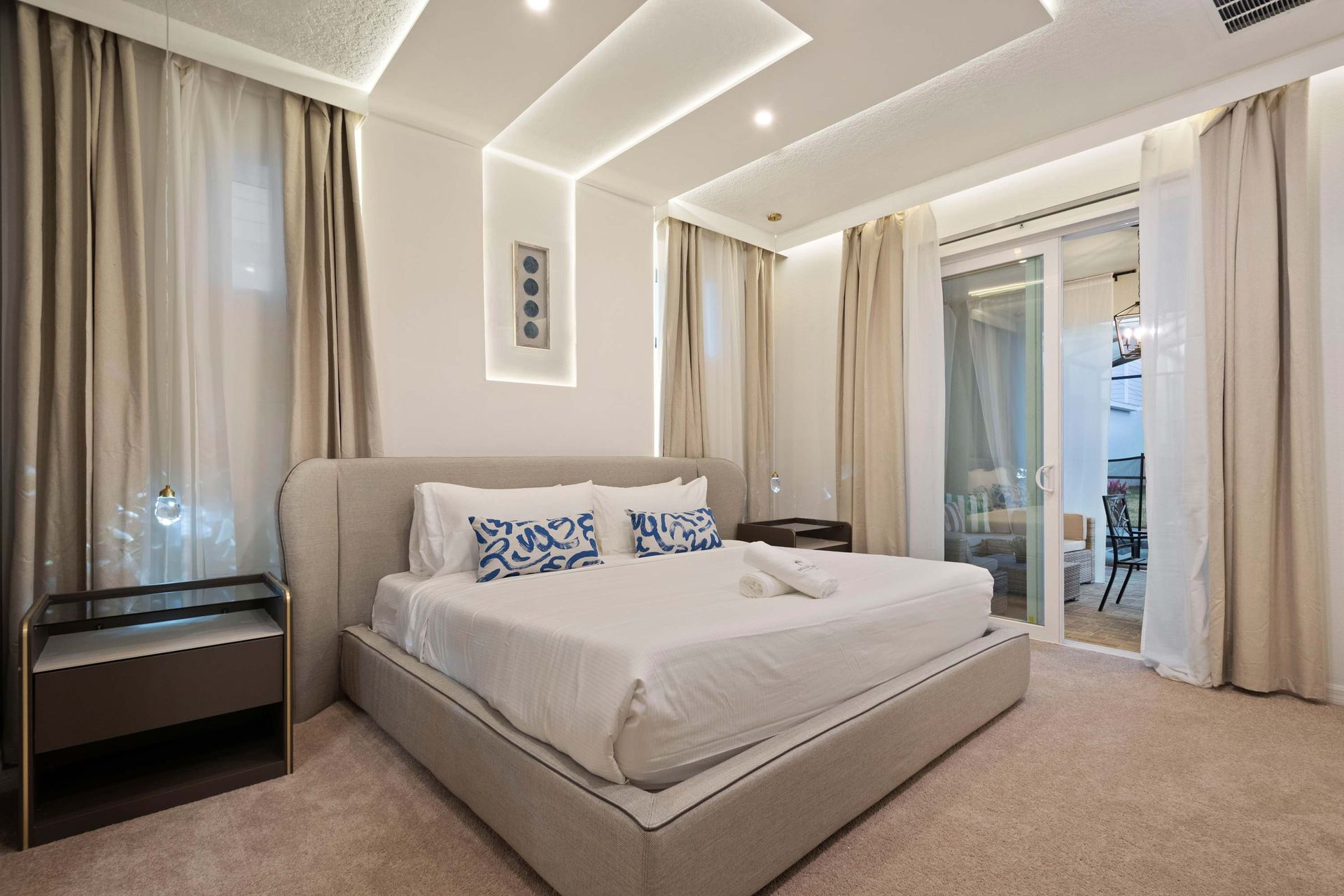 Elegant king suite with modern lighting, private patio access, and luxe bedding.
