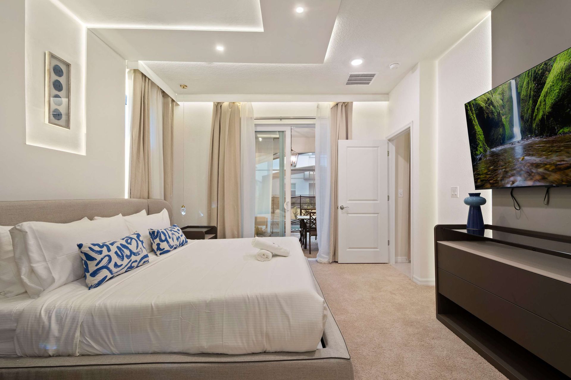 Modern king suite with sleek design, private patio access, and large smart TV.
