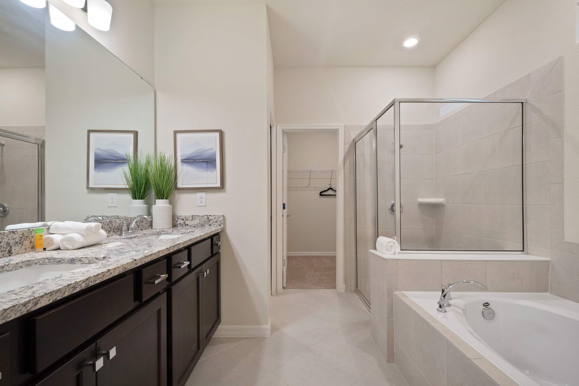 Luxurious bathroom with double vanity, soaking tub, glass shower, and walk-in closet.
