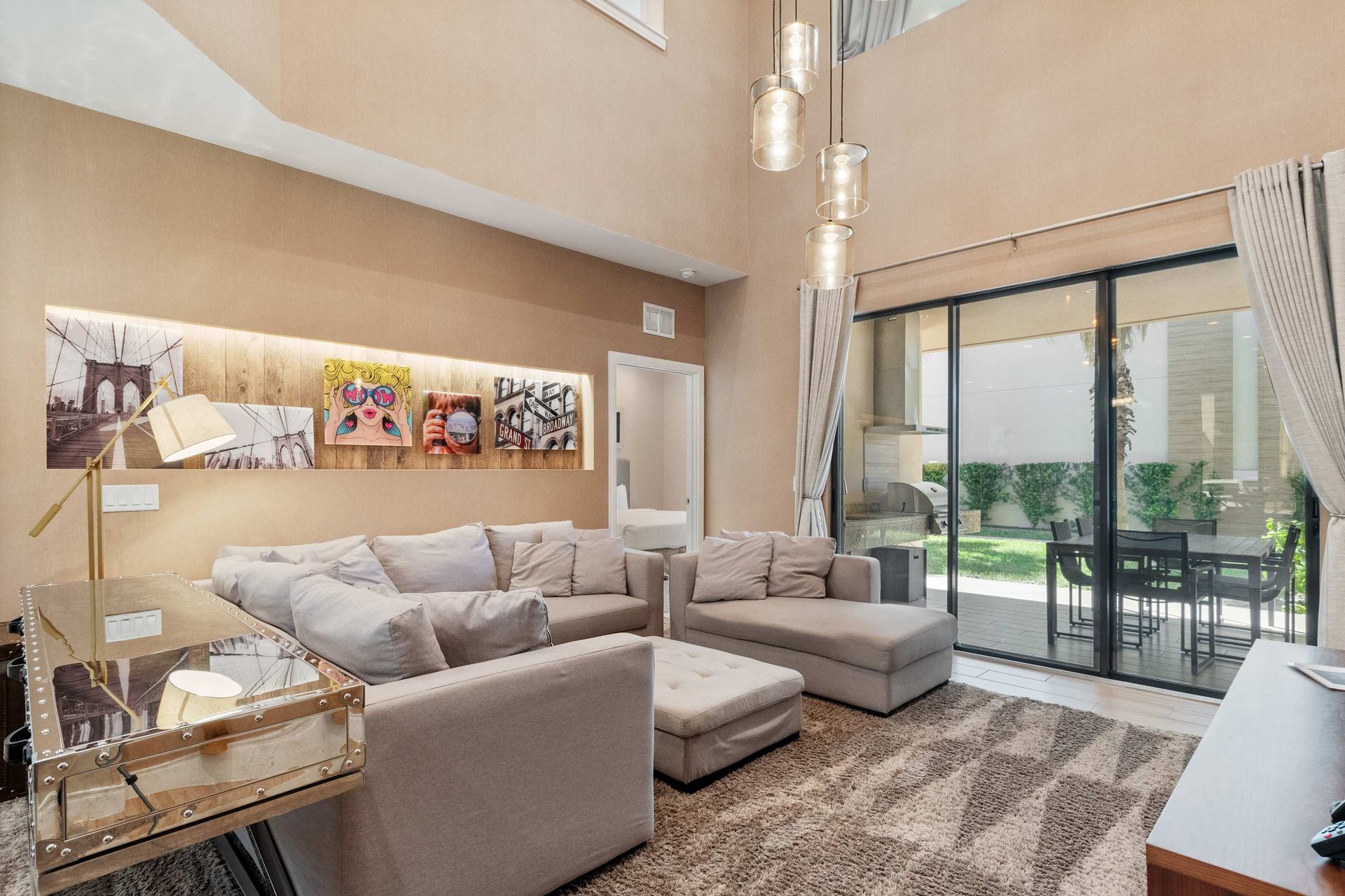 Spacious open living area with plush sectional, chic lighting, and modern kitchen.