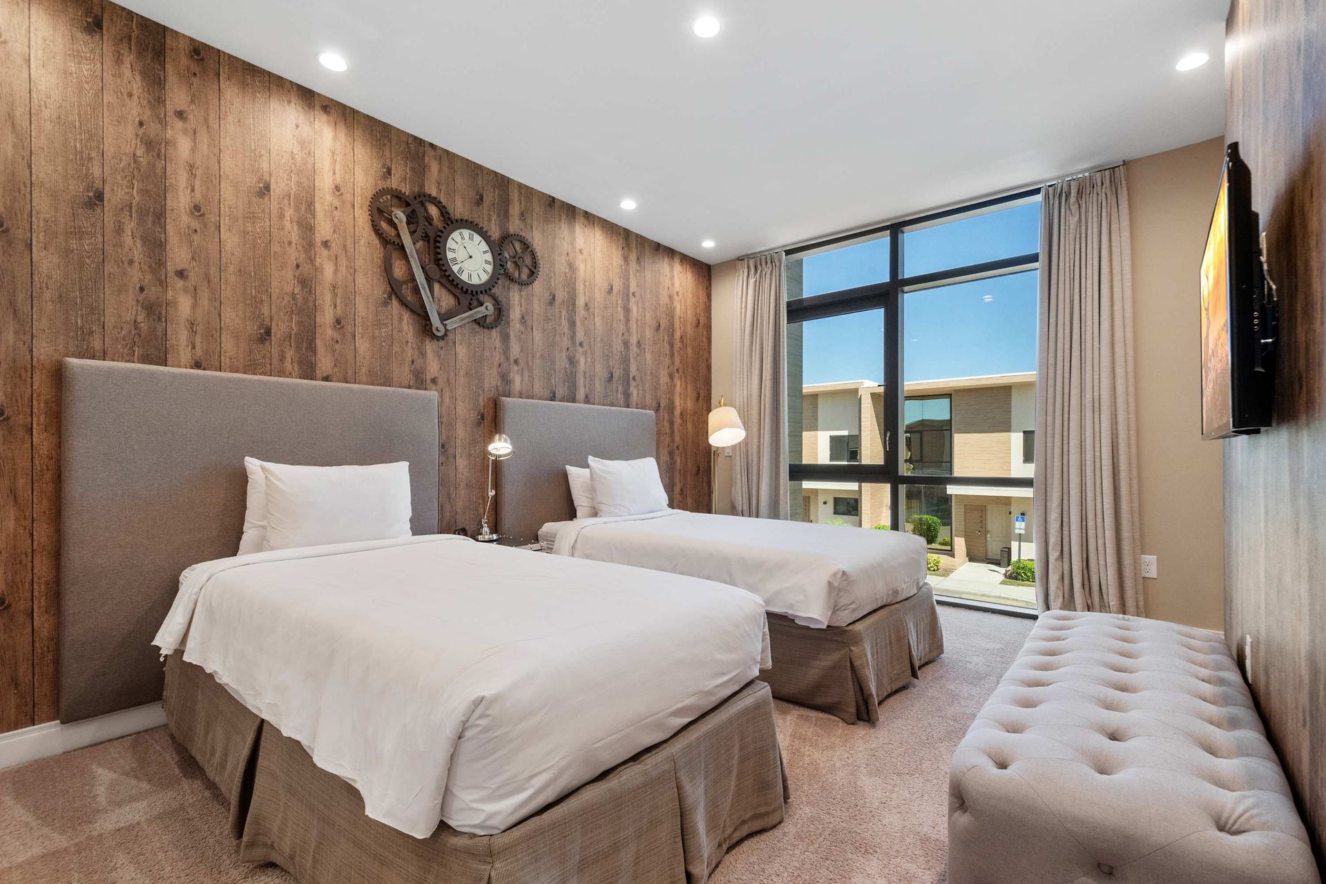 Cozy twin bedroom with rustic wood wall, unique clock decor, and warm inviting vibe.
