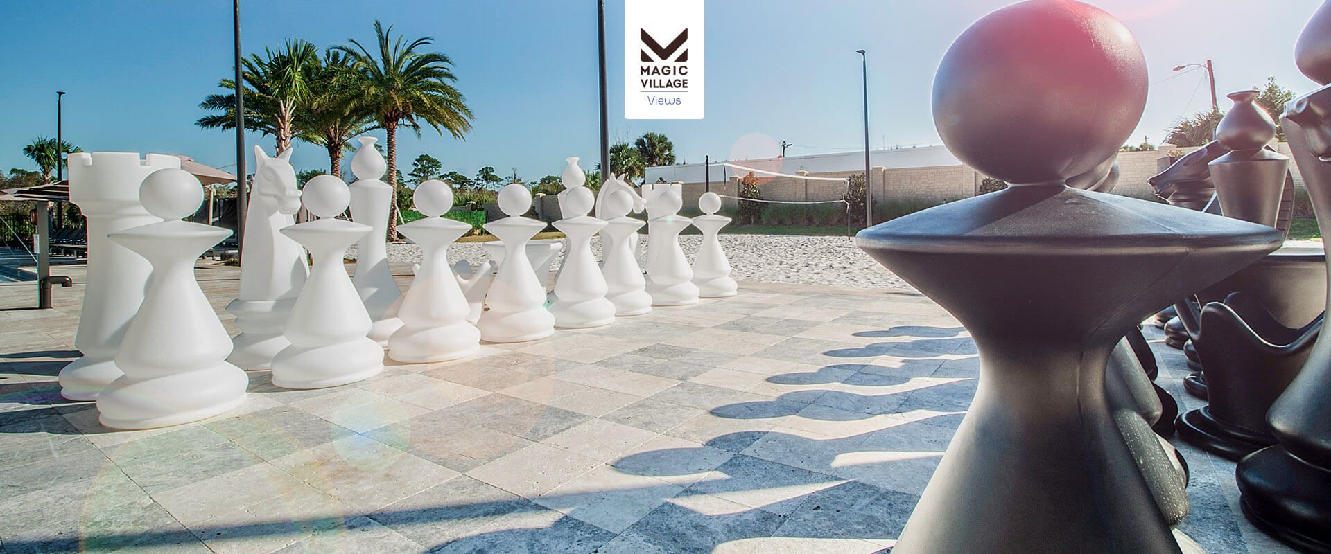 Outdoor giant chess set under palm trees, perfect for fun and relaxation in sunshine.