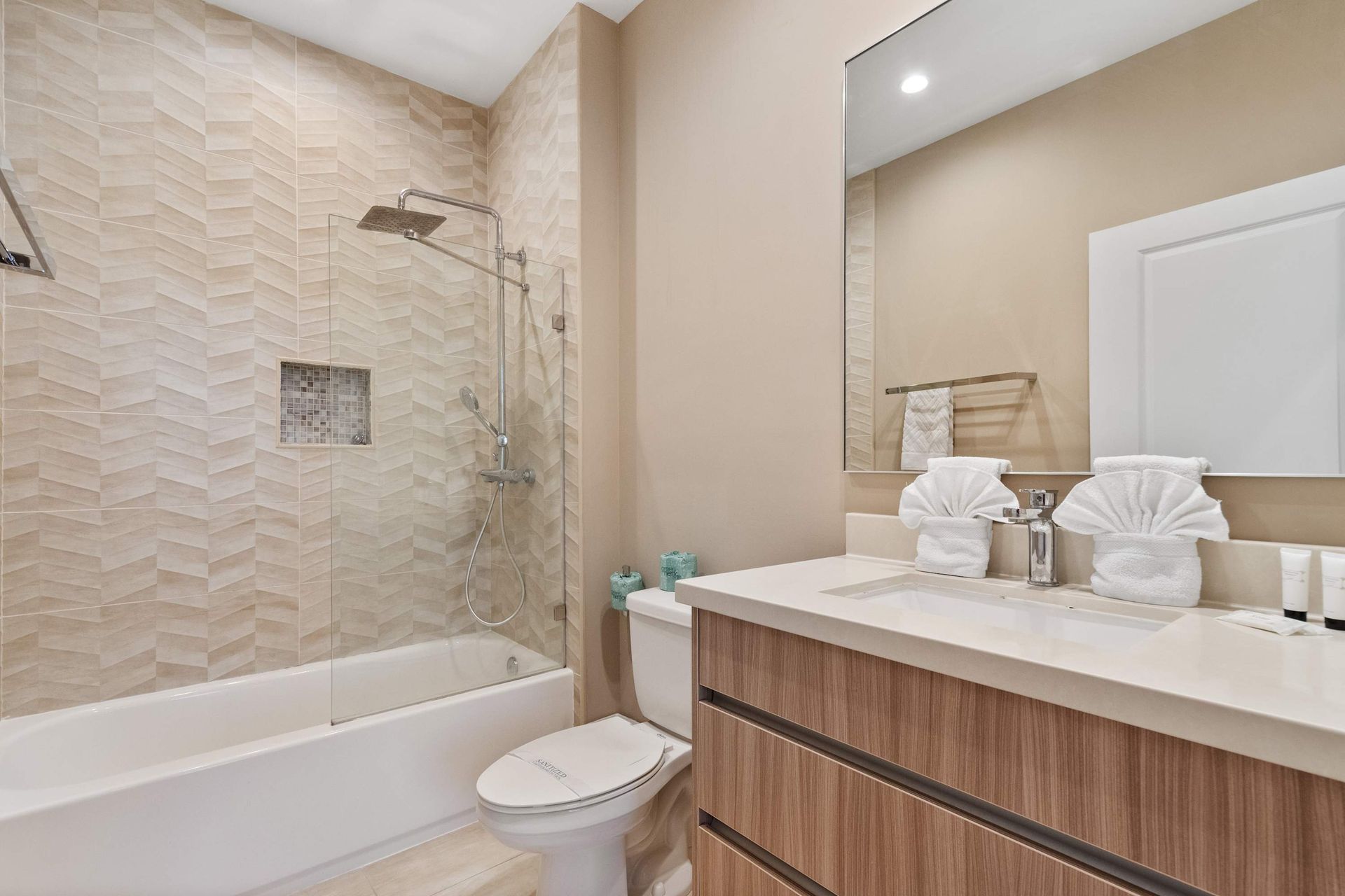 Stylish bathroom with modern vanity, large mirror, and elegant shower-tub combo.