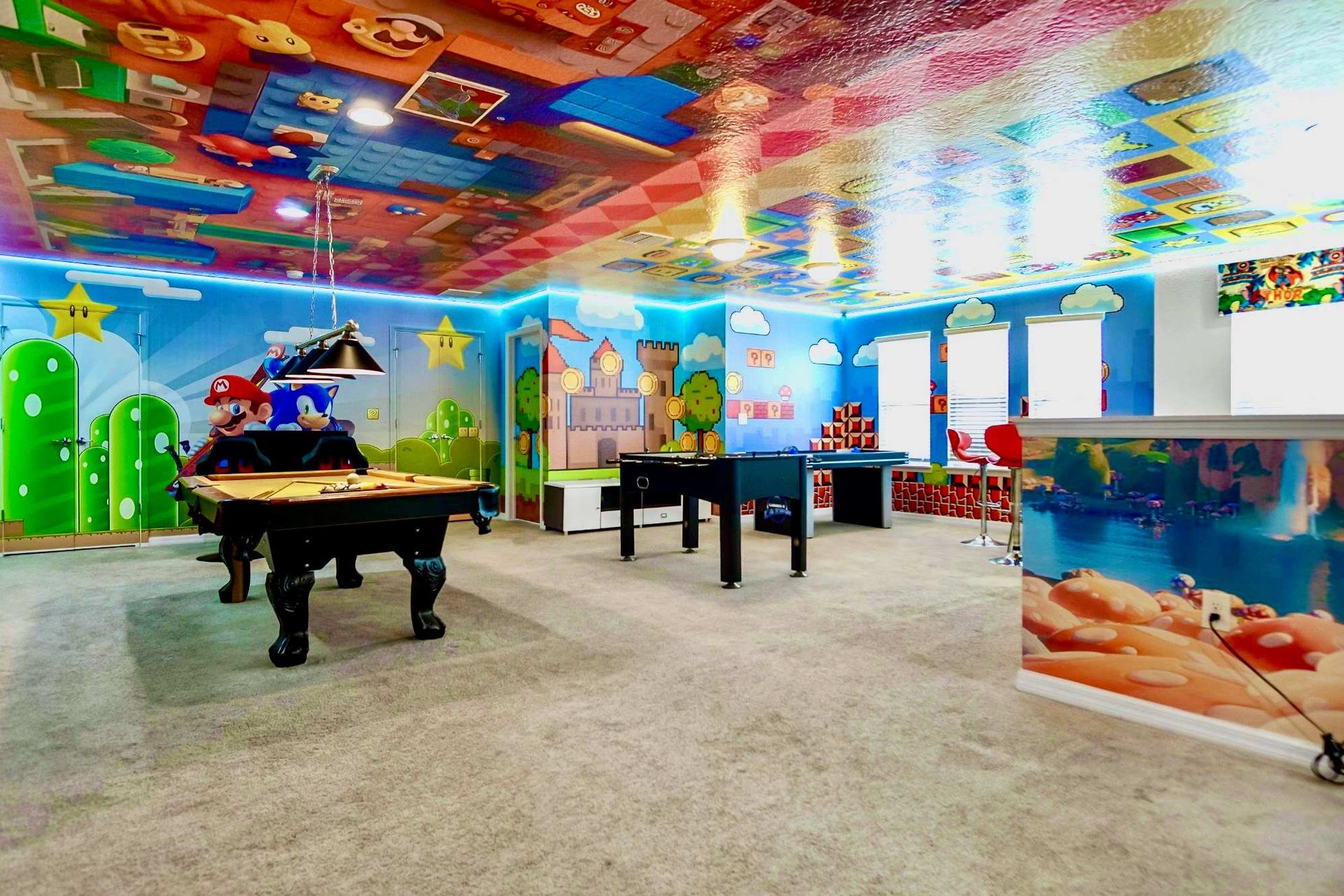 Massive themed game room with pool, foosball, bar seating, and vibrant decor.