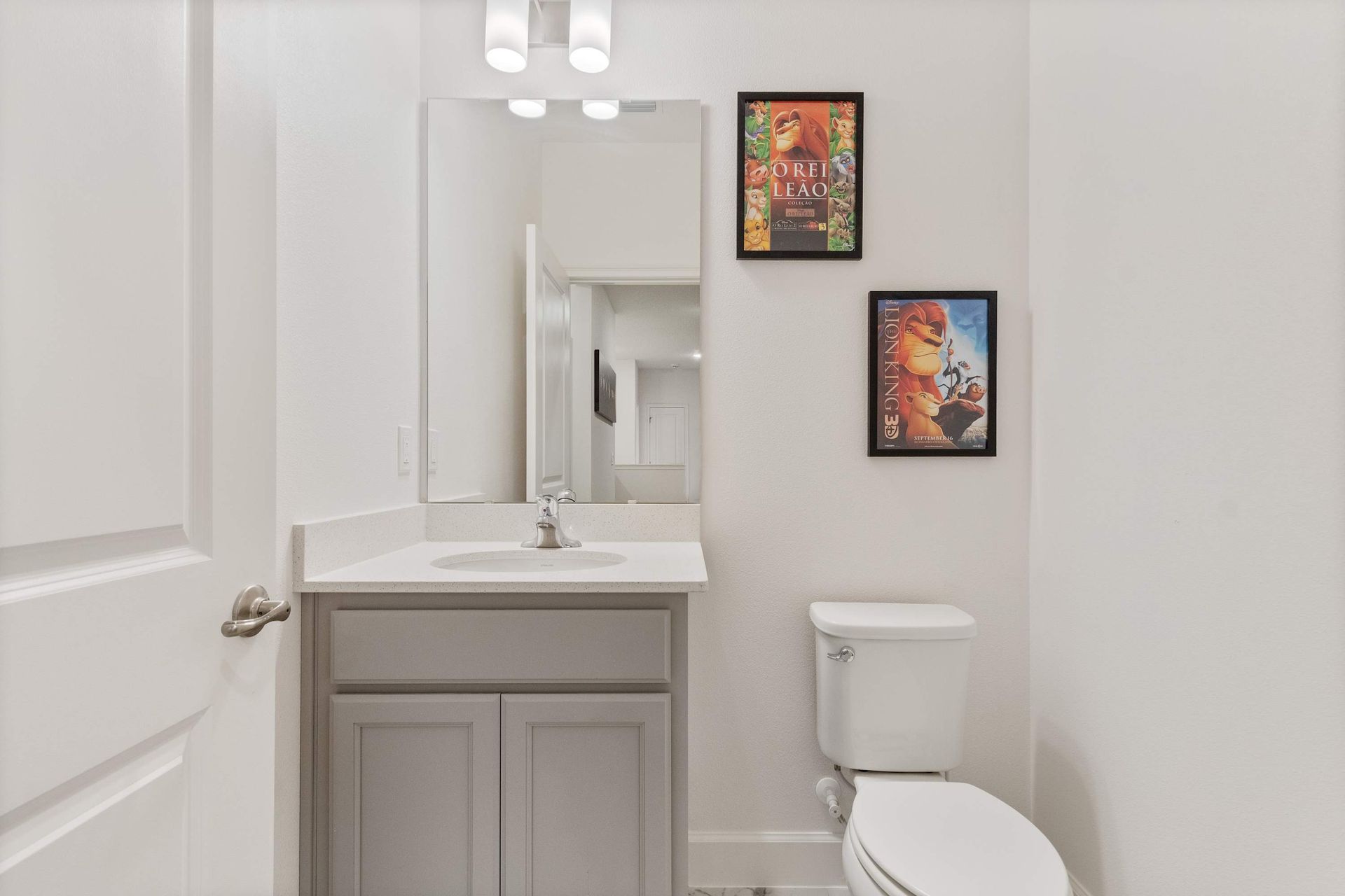 Compact and modern half-bath with fun artwork, sleek vanity, and bright lighting
