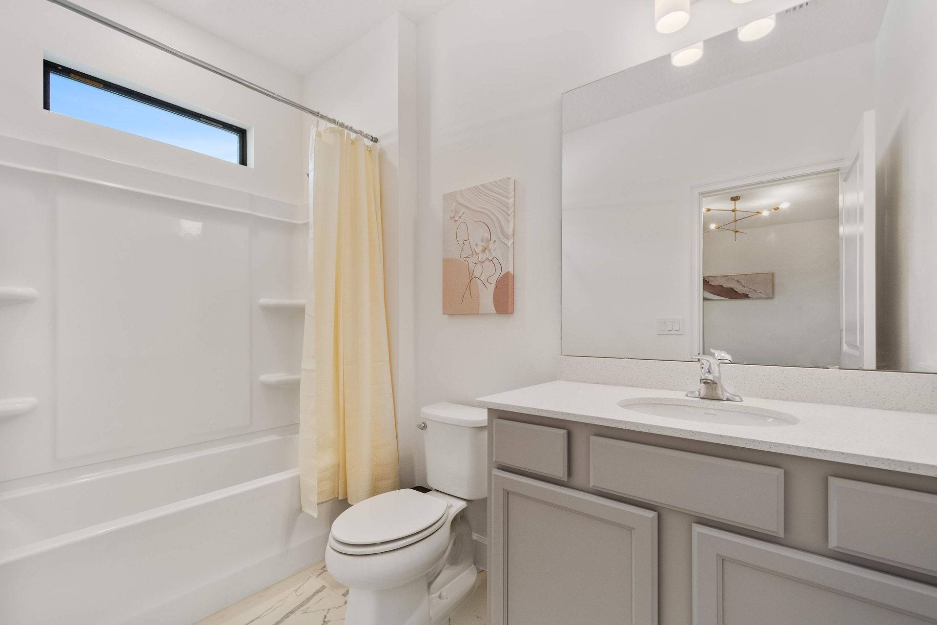 Soft and serene bathroom with light yellow accents, modern vanity, and full tub combo
