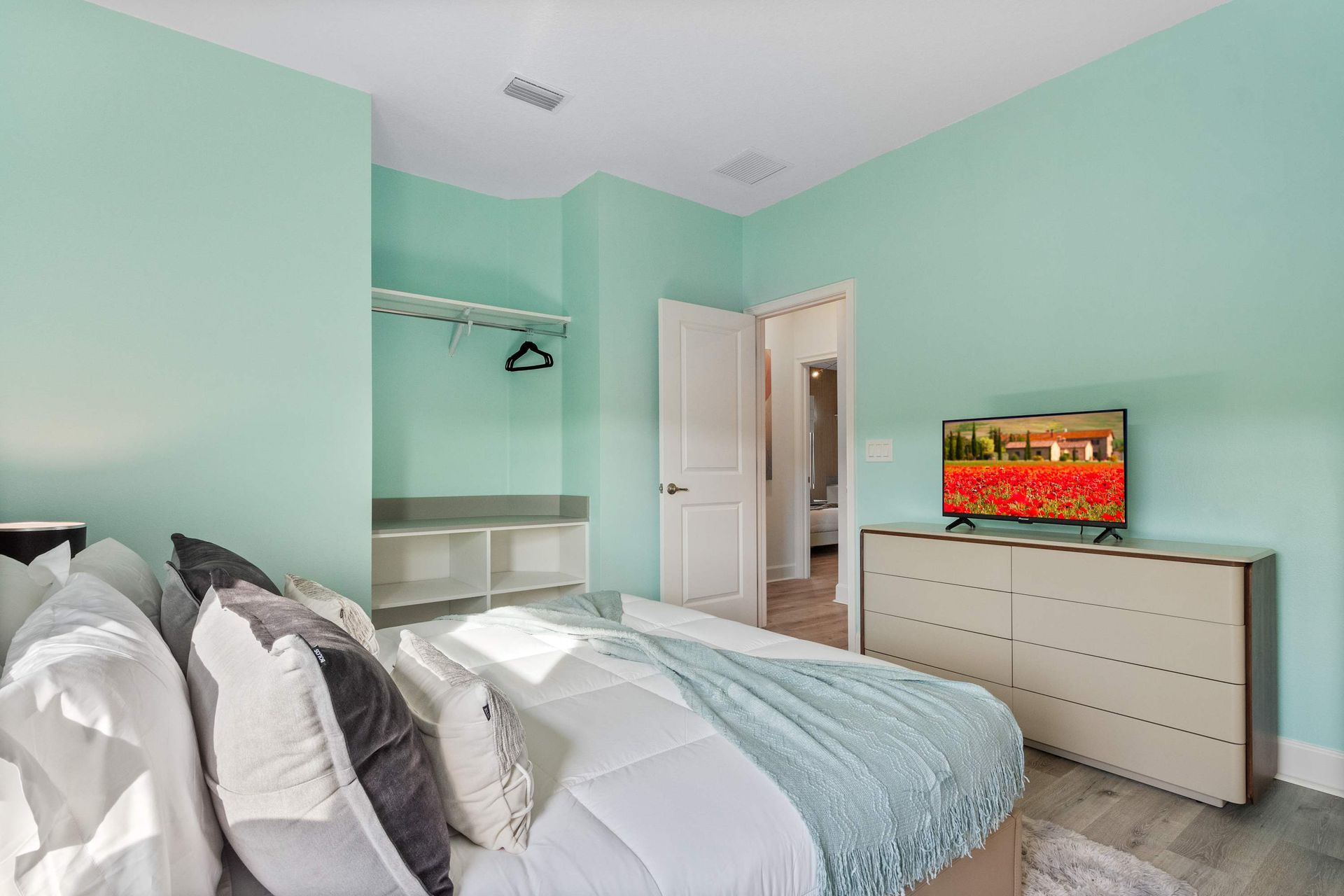 Chic bedroom with retro glam touches, mint walls, plush bedding, and en-suite bath
