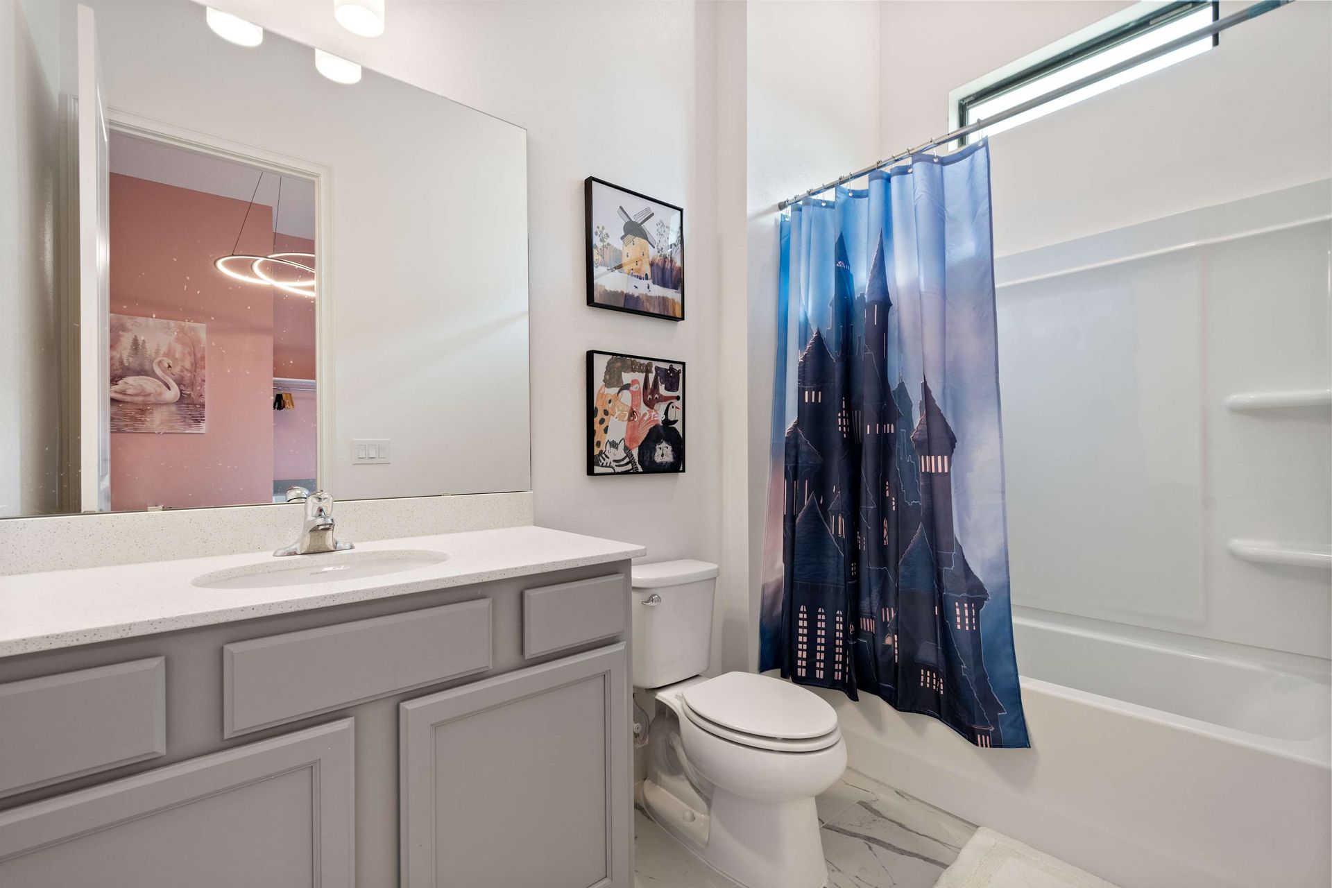 Whimsical bathroom with castle-themed shower curtain, modern vanity, and bright lighting
