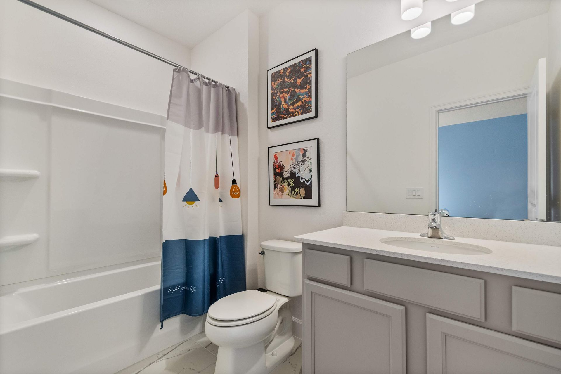 Cheerful bathroom with colorful shower curtain, playful art, and modern gray vanity
