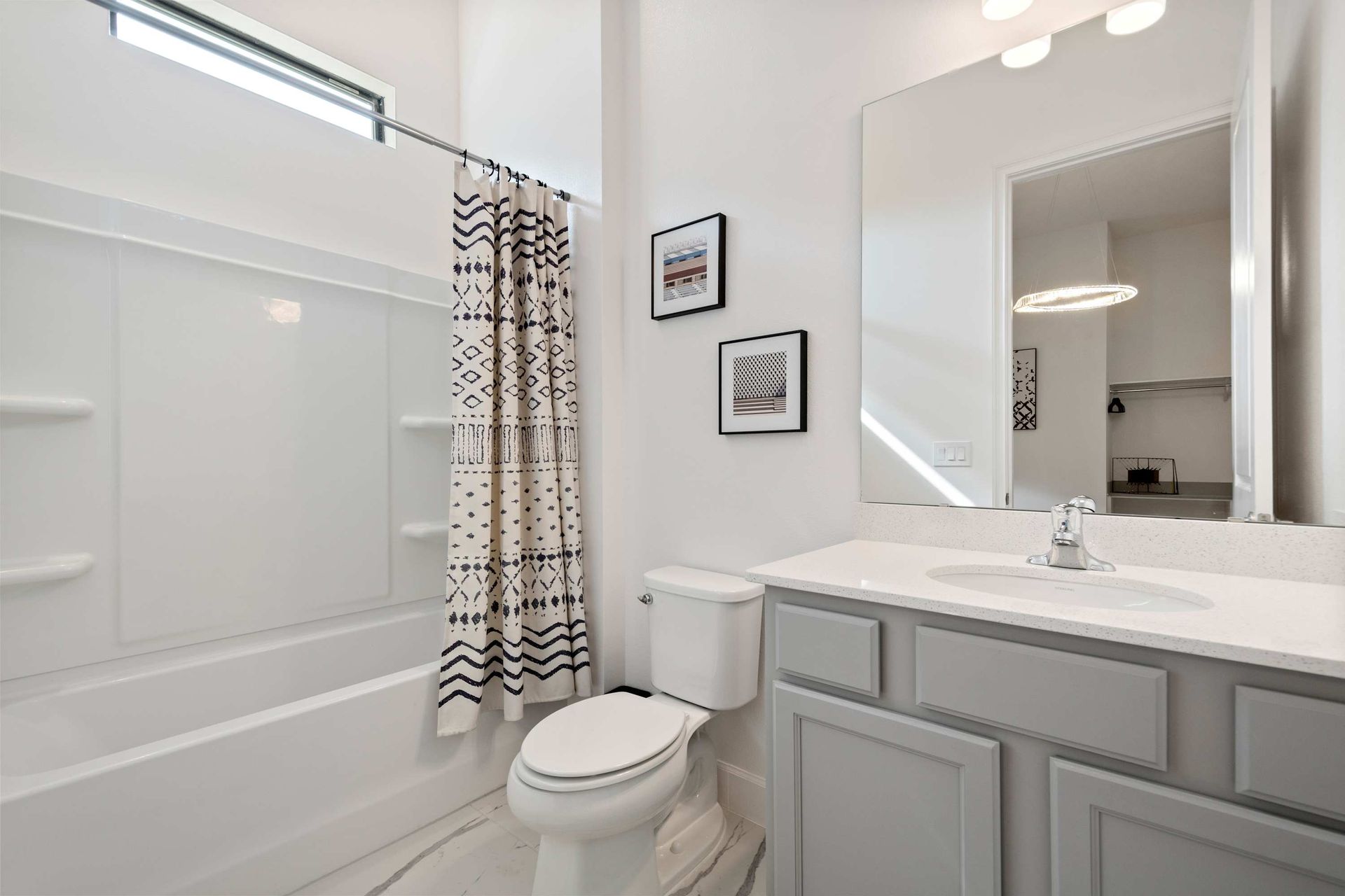 Bright and modern bathroom with tub/shower combo, sleek vanity, and clean finishes
