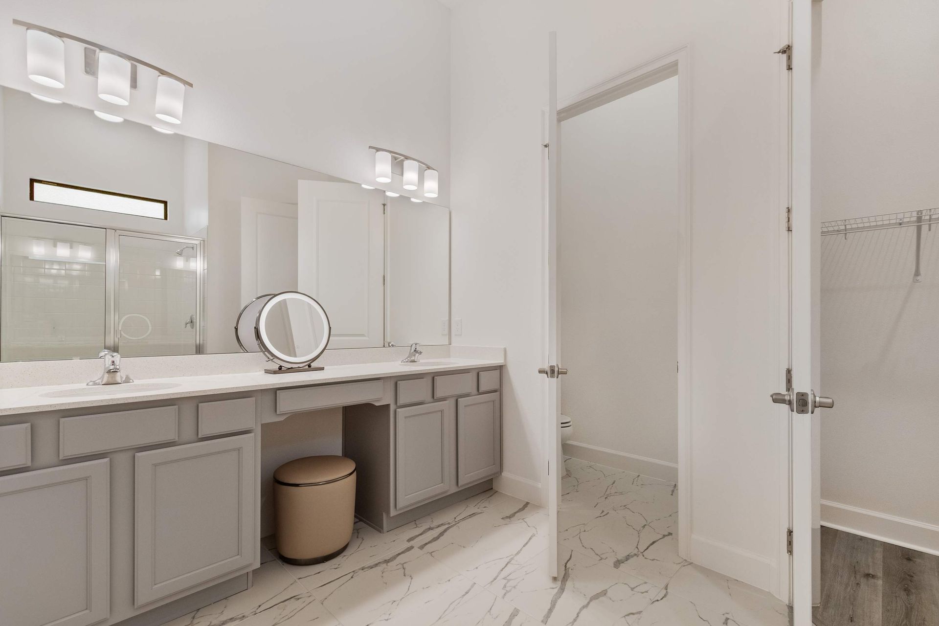 Spacious ensuite bath with double vanity, makeup station, and walk-in closet access
